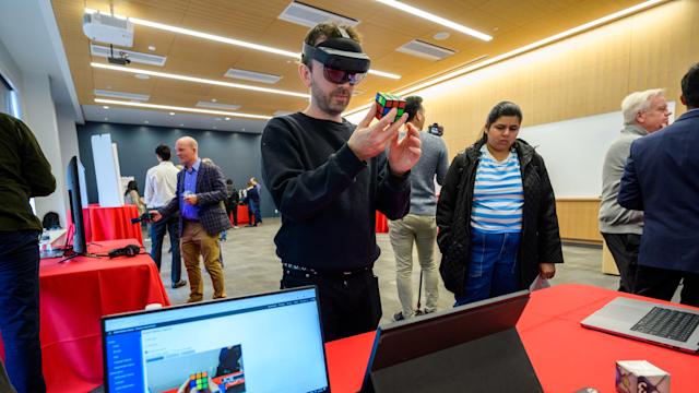 Industry Torchbearers Information Technology - a man uses technology to solve a Rubik's cube