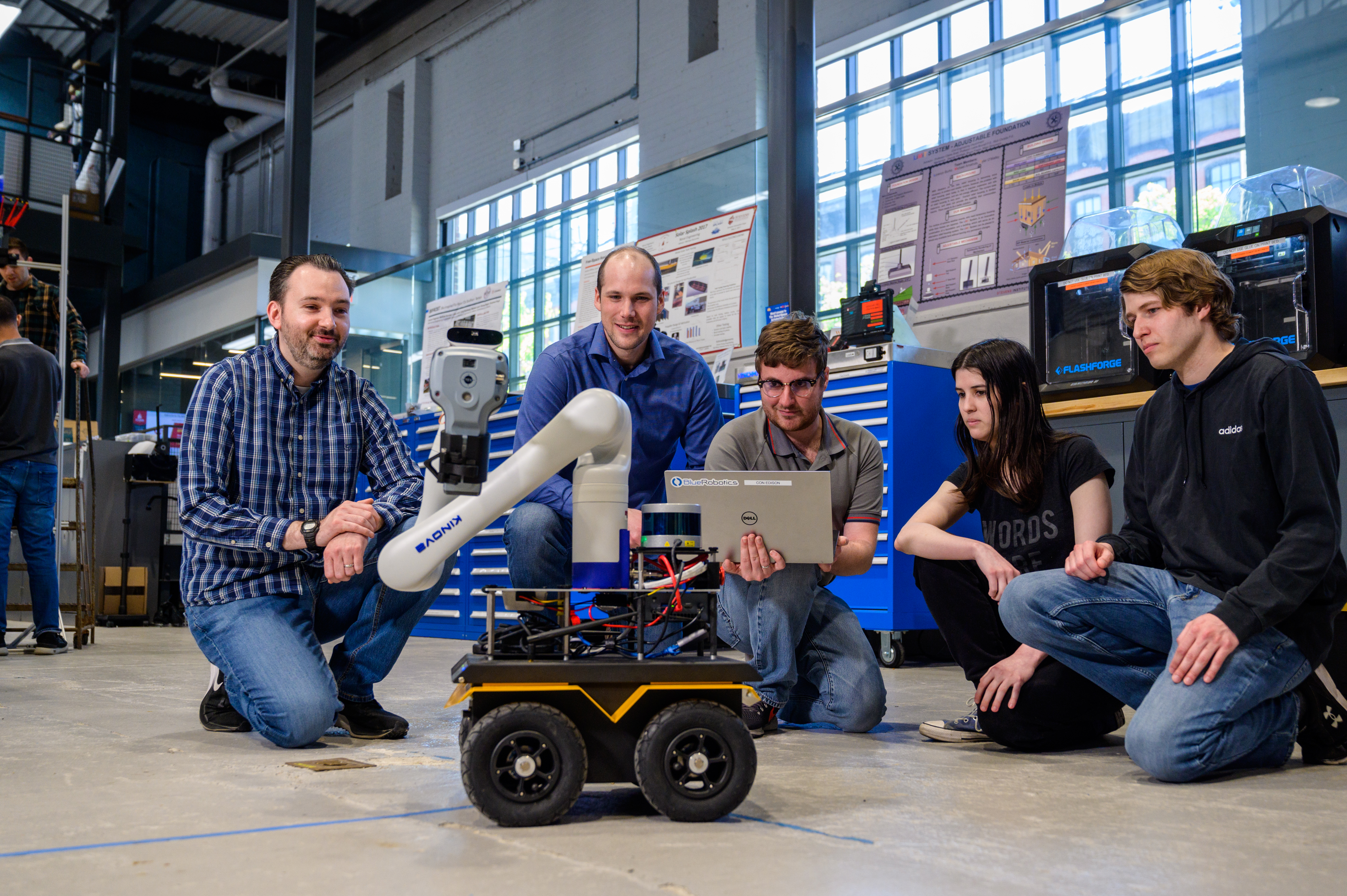 Individuals gather on a lab floor around a robot