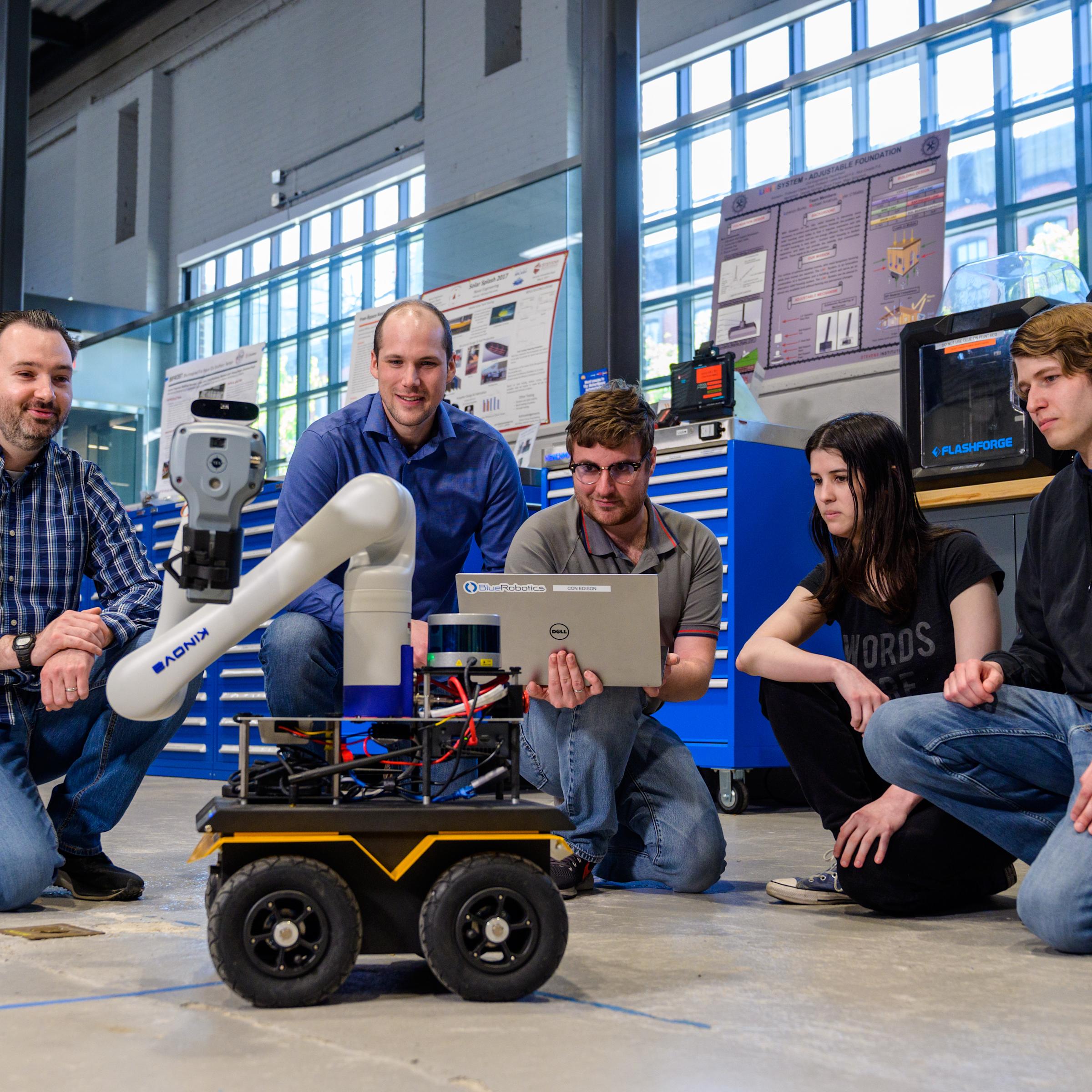 Individuals gather on a lab floor around a robot