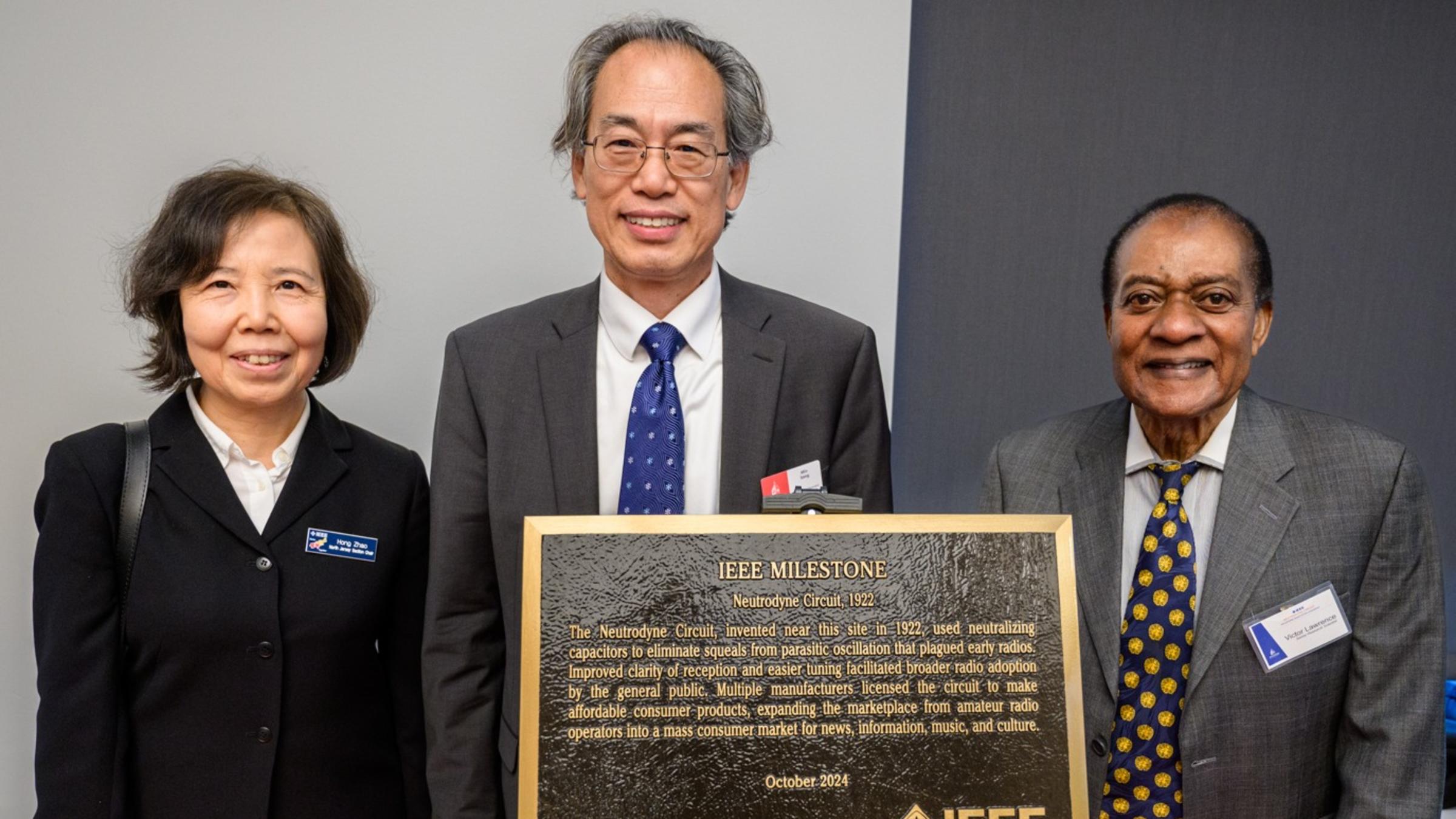Hong Zhao, Min Song and Victor Lawrence pose in front of an IEEE Milestone plaque.