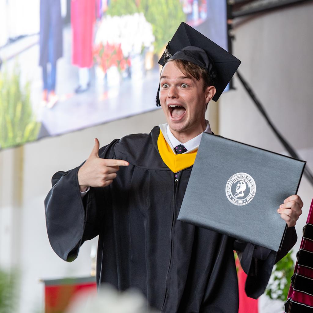 An excited student at Commencement receives his diploma