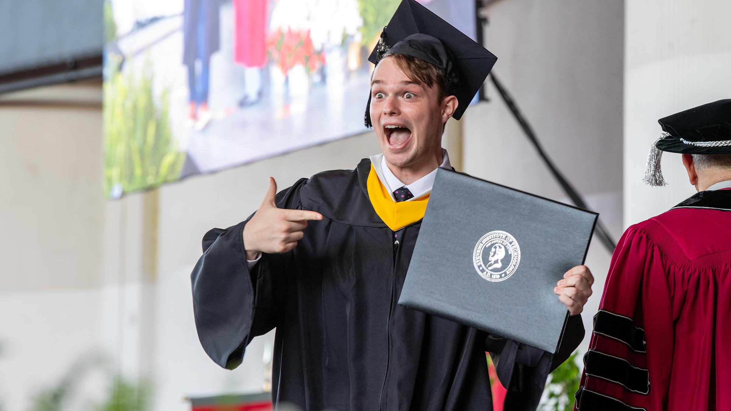 An excited student at Commencement receives his diploma