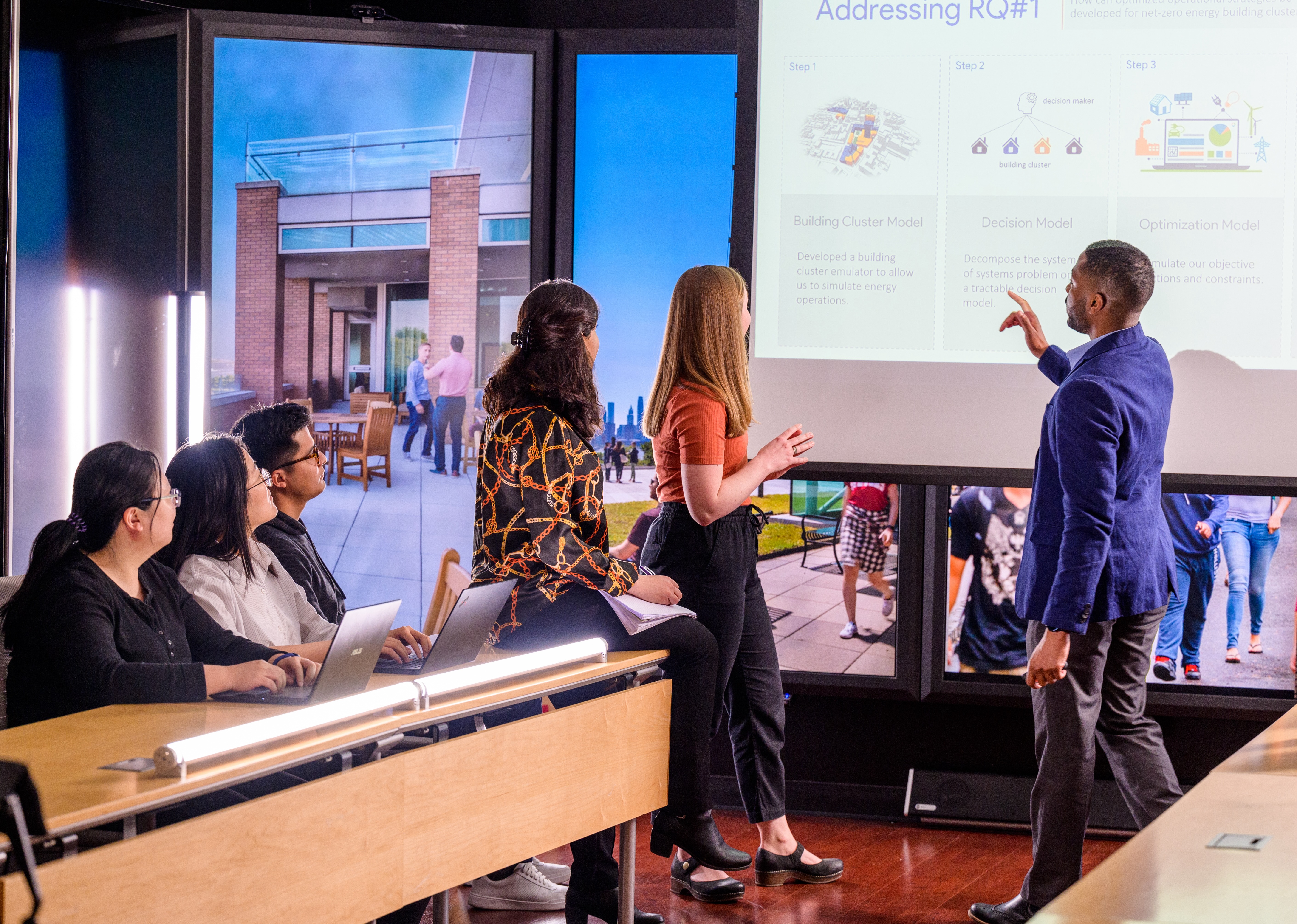 Students and a faculty member review information on a presentation screen in the immersion laboratory.