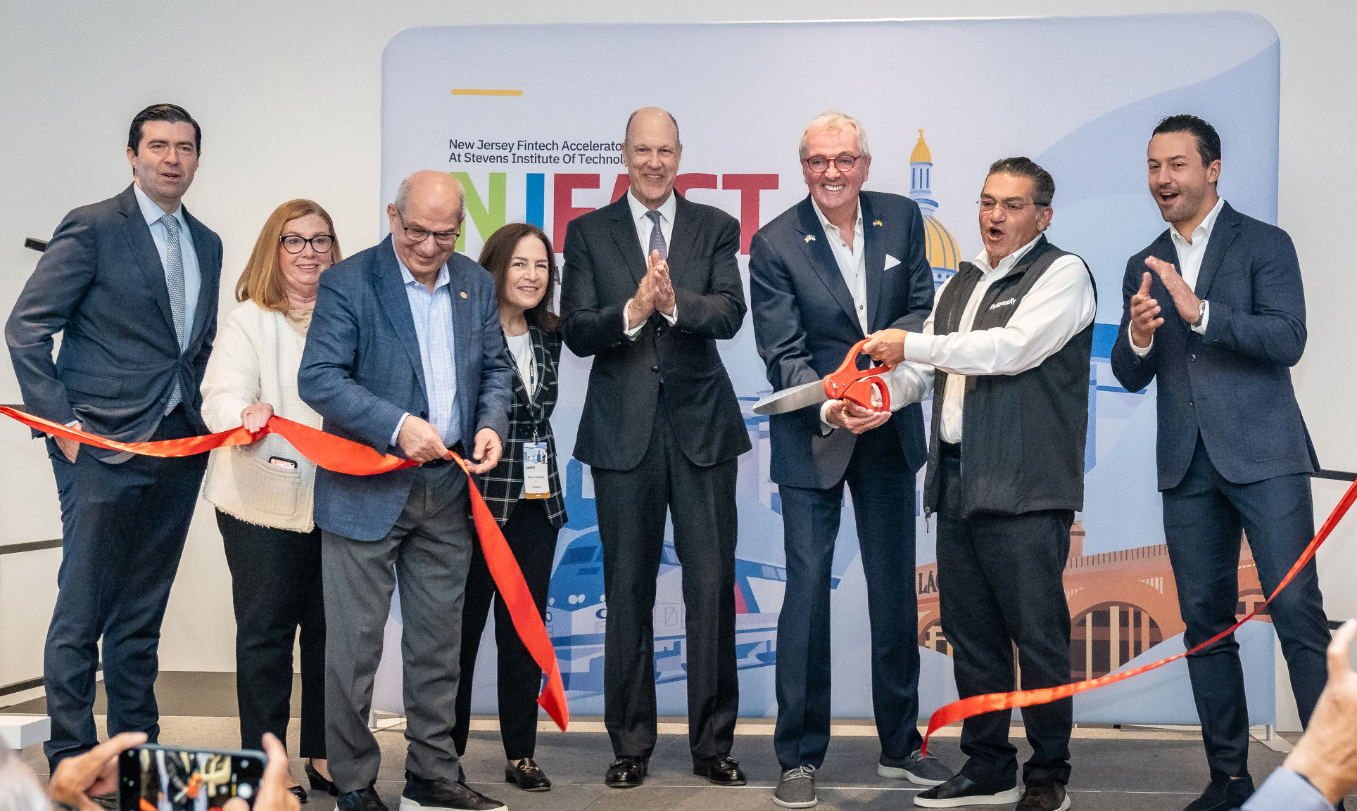 Leaders of NJ FAST cut the ribbon with large scissors.