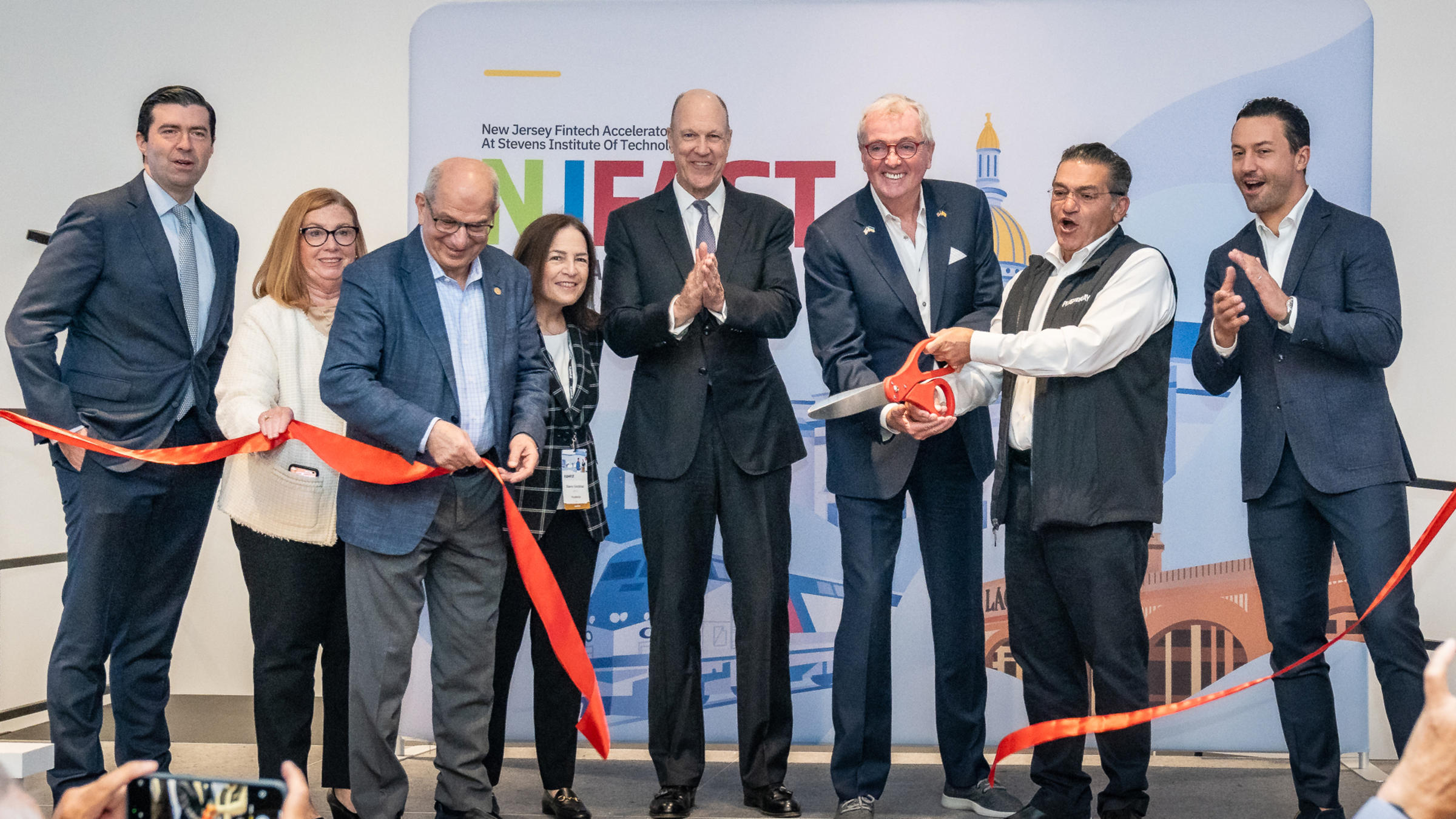 Leaders of NJ FAST cut the ribbon with large scissors.