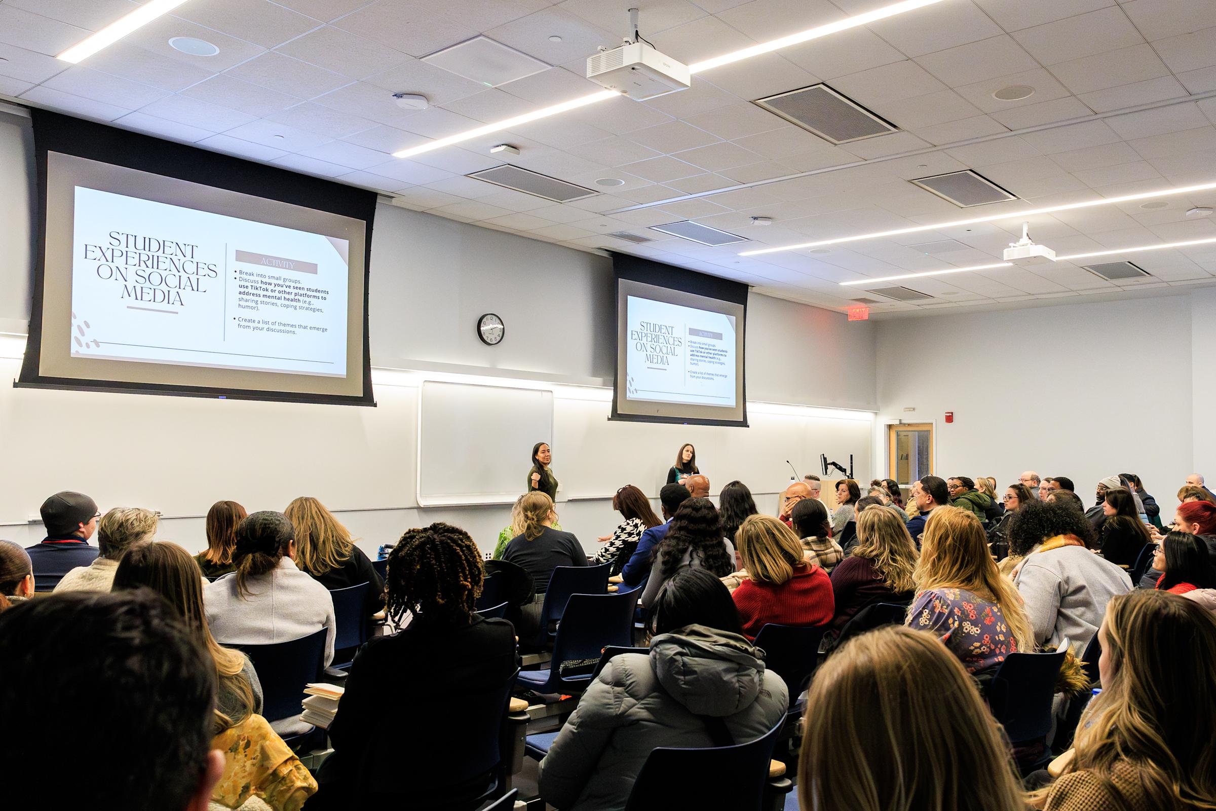 Two women teach a classroom full of attendees.