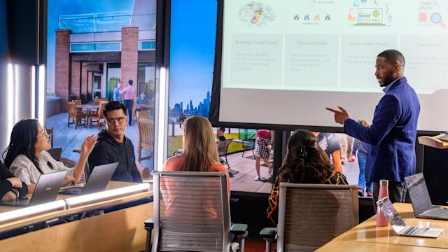 Students gather in a classroom with professor