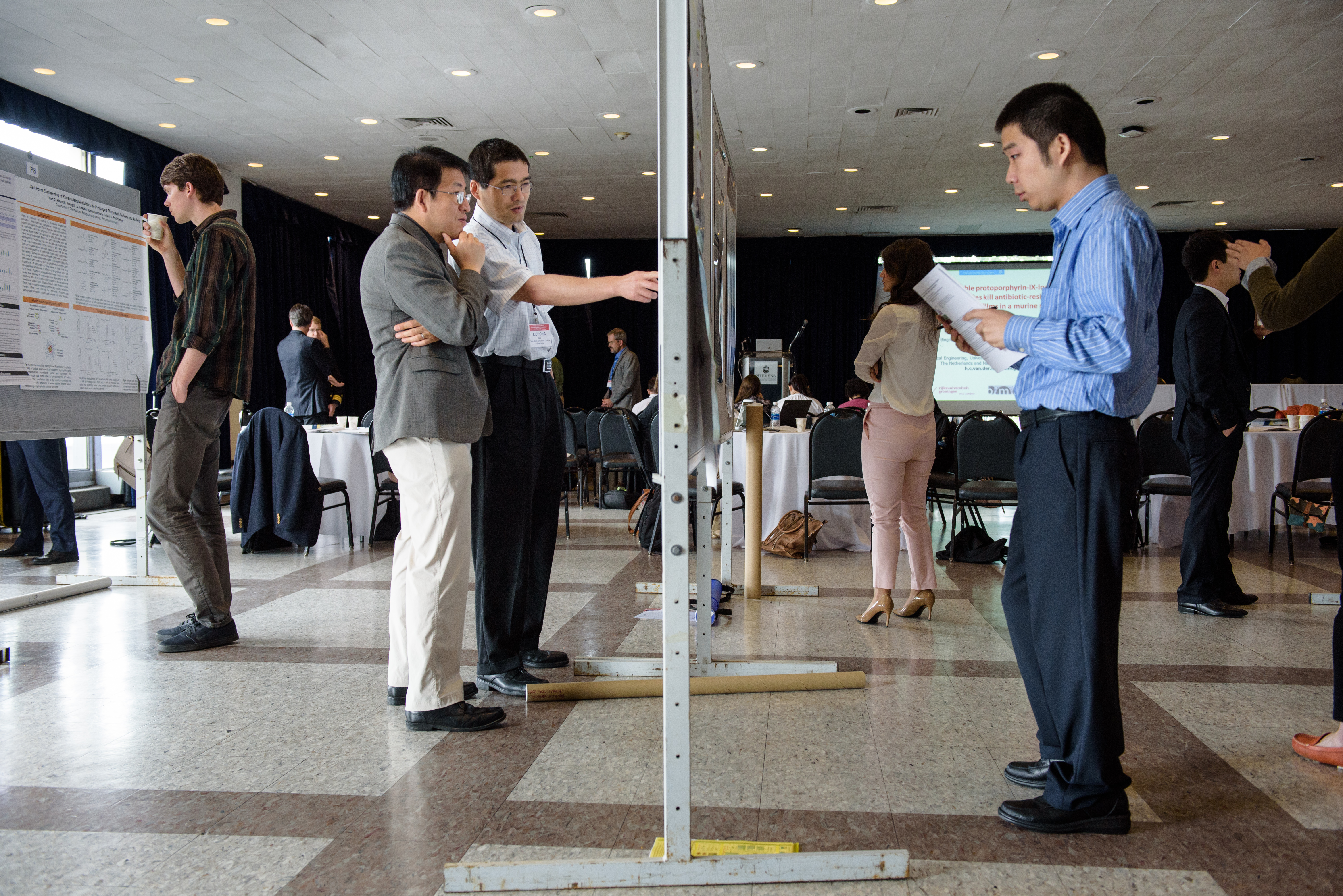 Faculty and students observe a poster session at the Stevens Conference on Bacteria-Material Interactions.