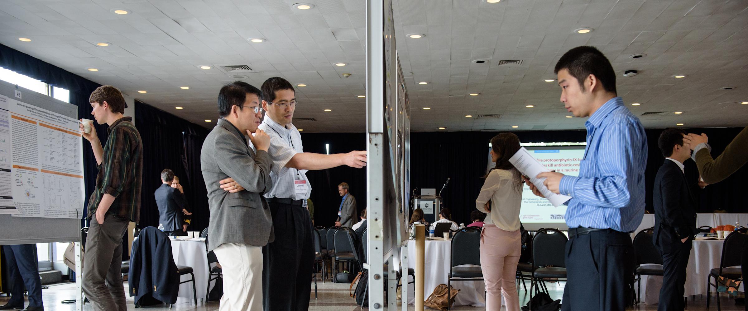 Faculty and students observe a poster session at the Stevens Conference on Bacteria-Material Interactions.