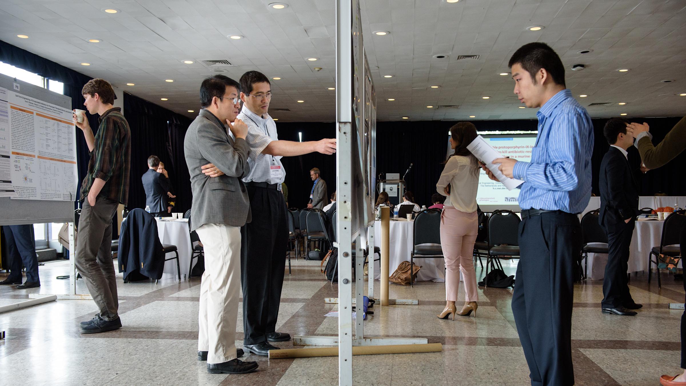 Faculty and students observe a poster session at the Stevens Conference on Bacteria-Material Interactions.