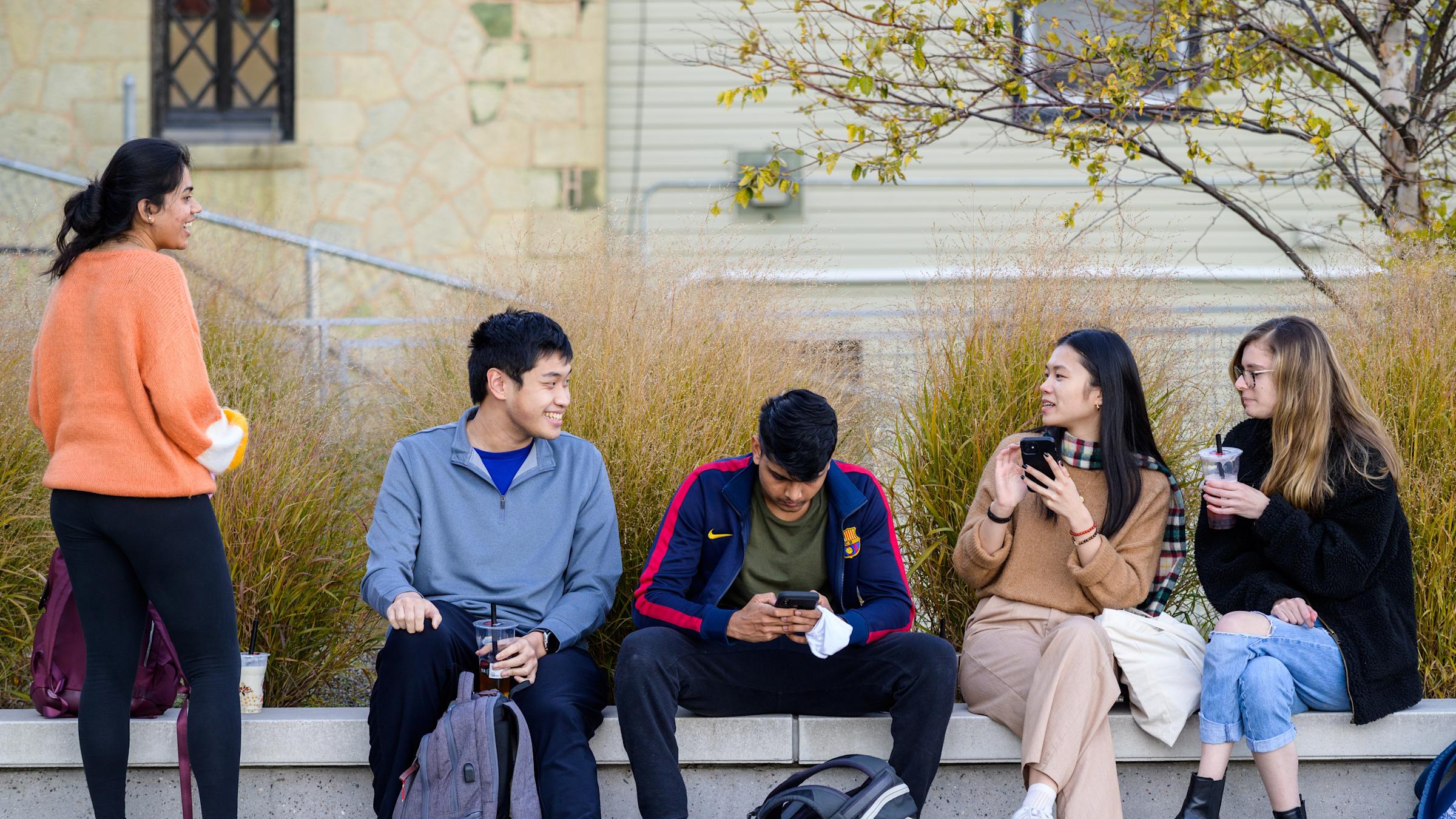 Five Stevens students sitting on a bench, smiling.