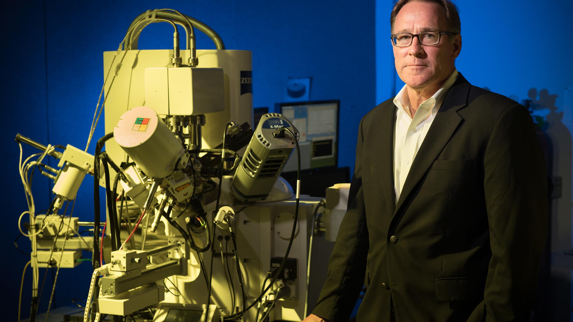 Professor Matt Libera stands next to a large piece of lab equipment.