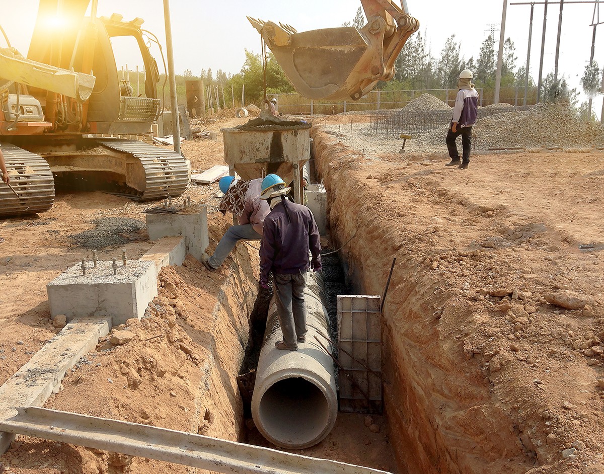 A dirt trench with a large pipe running through it.