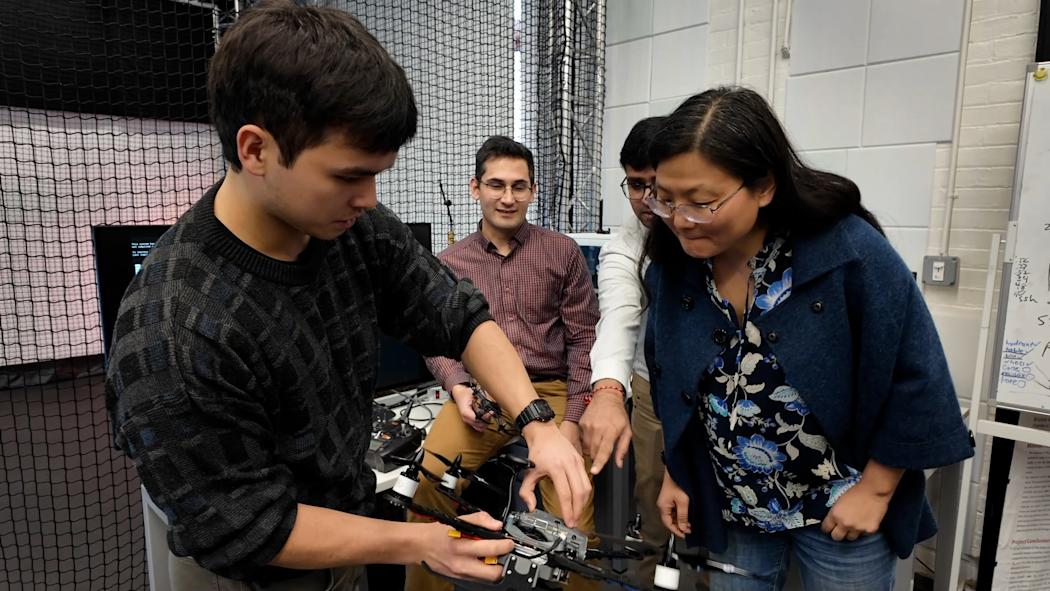 Ying Wang and a group of students inspect a drone.