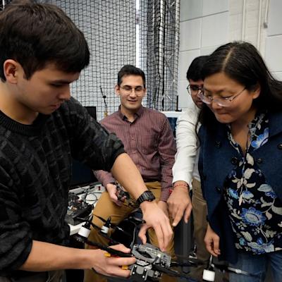 Ying Wang and a group of students inspect a drone.