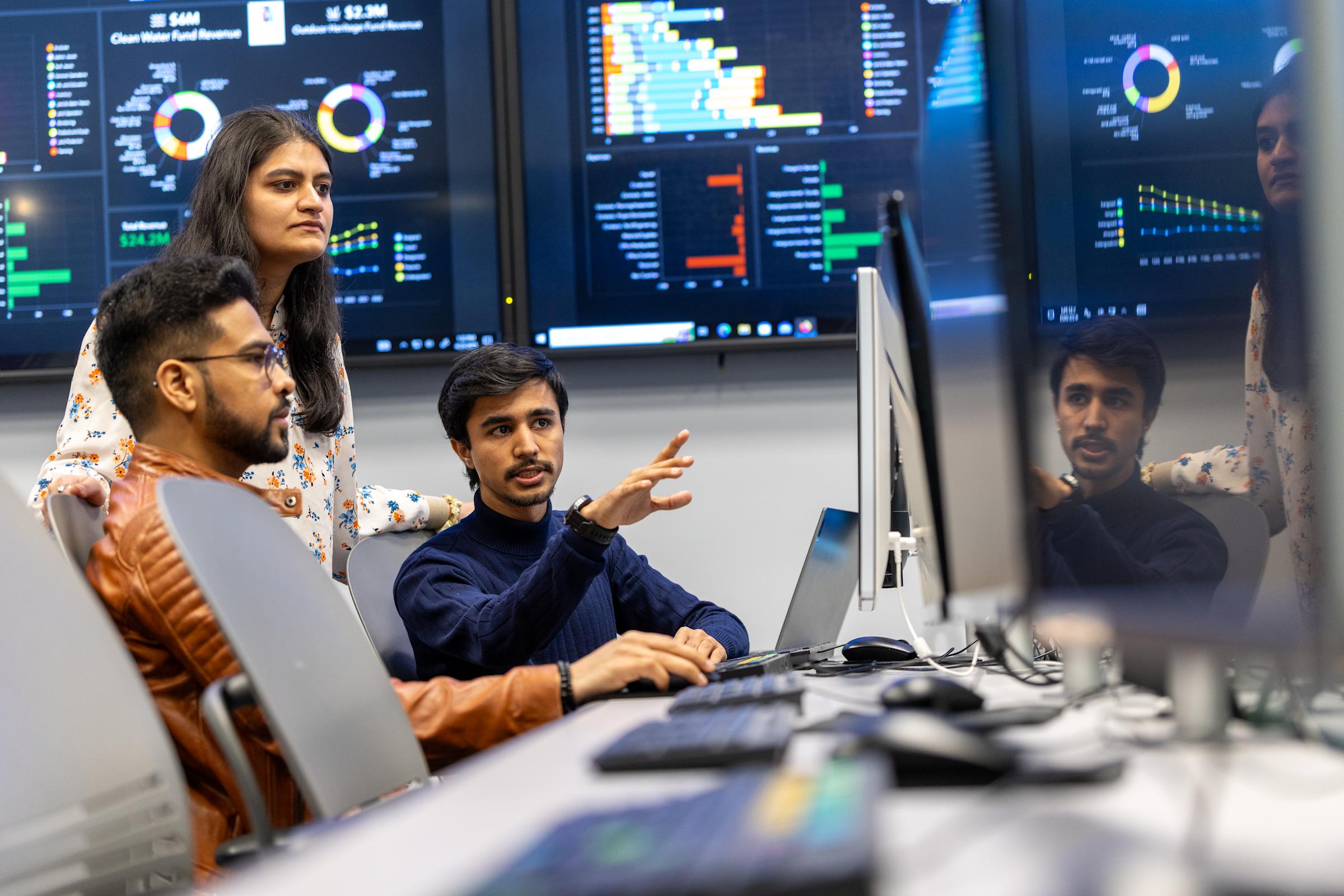 Image of individuals talking near computer screens