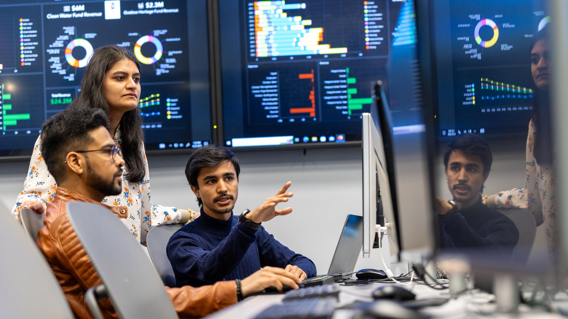 Image of individuals talking near computer screens