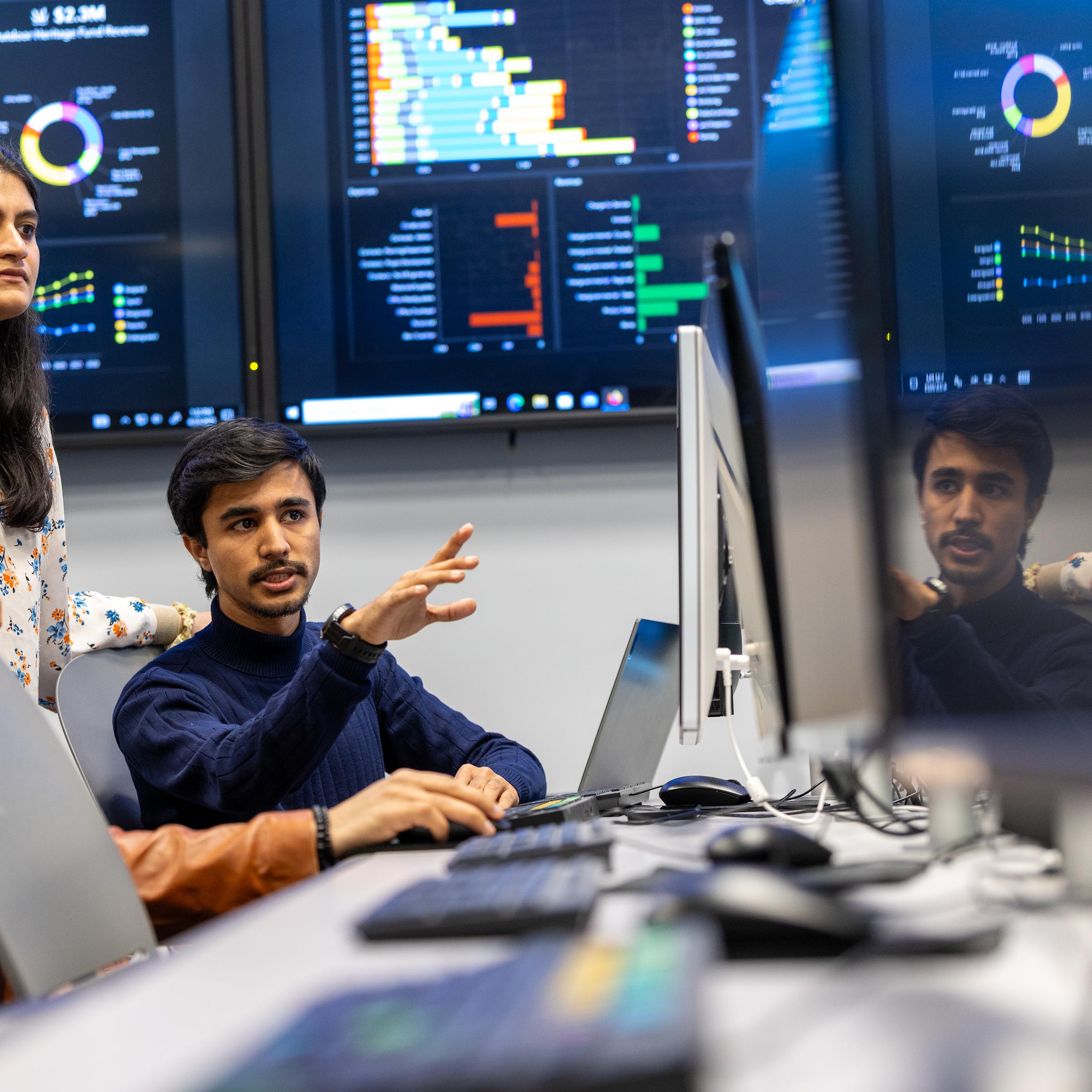 Image of individuals talking near computer screens