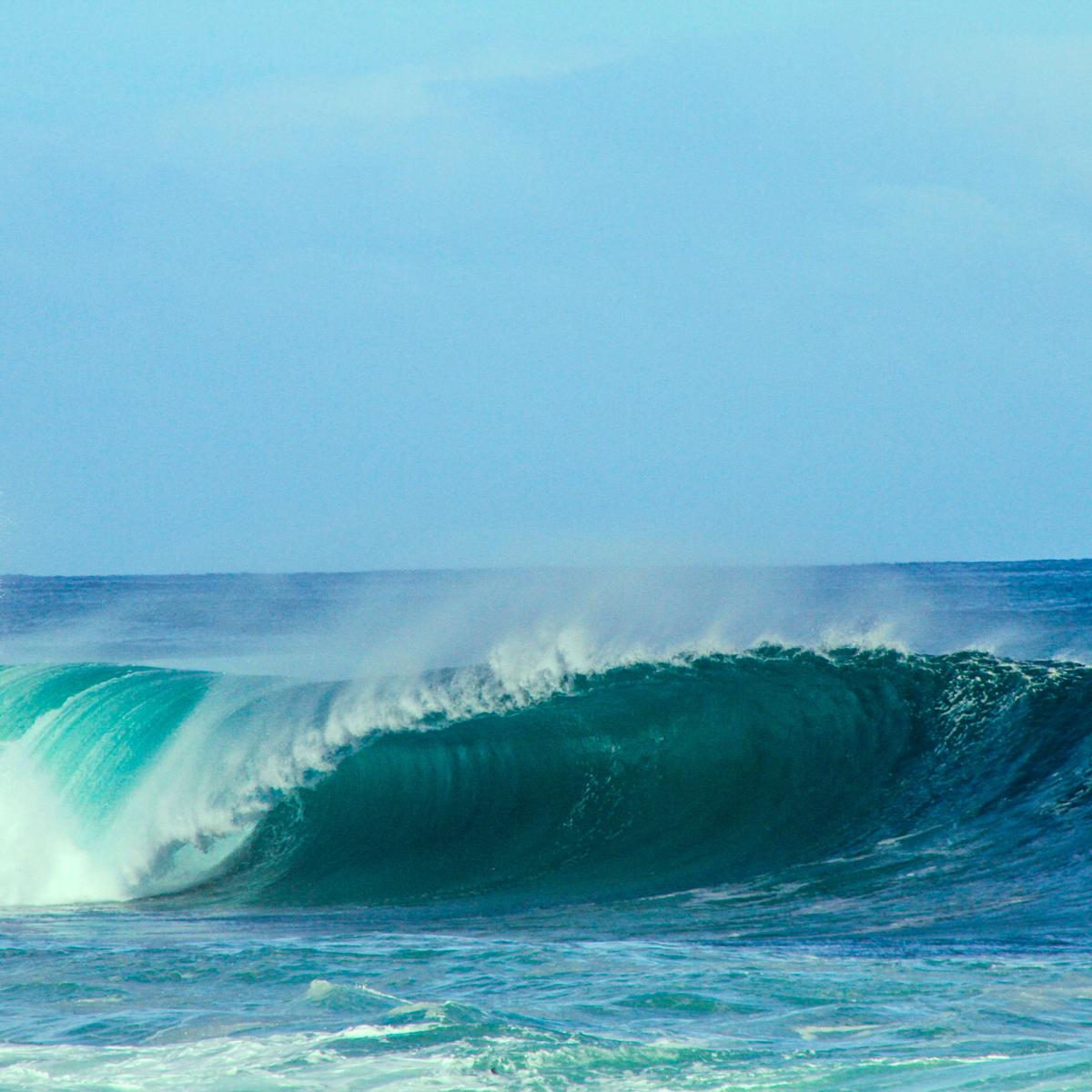 A blue breaking wave in the ocean, representing wave power