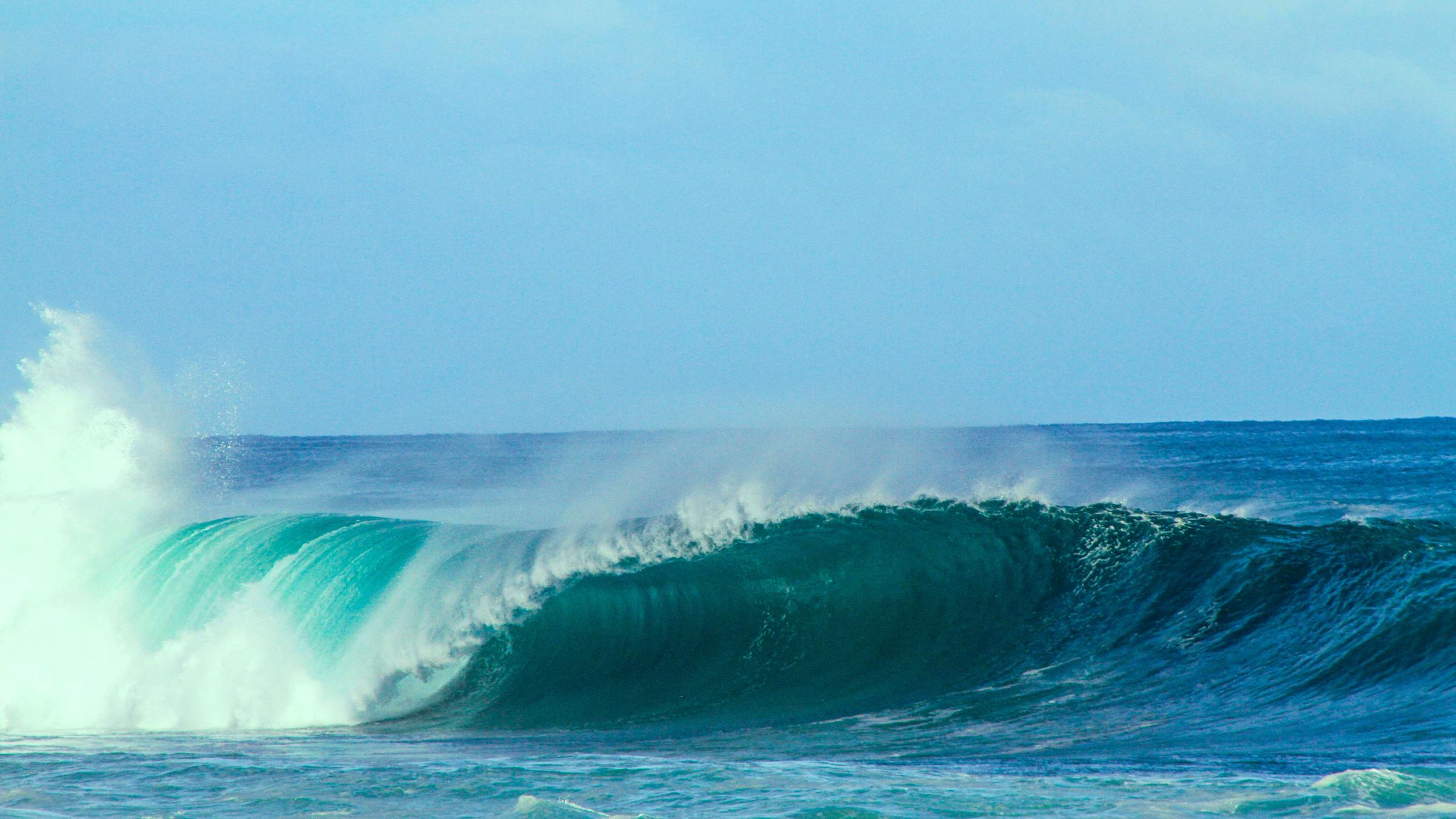 A blue breaking wave in the ocean, representing wave power
