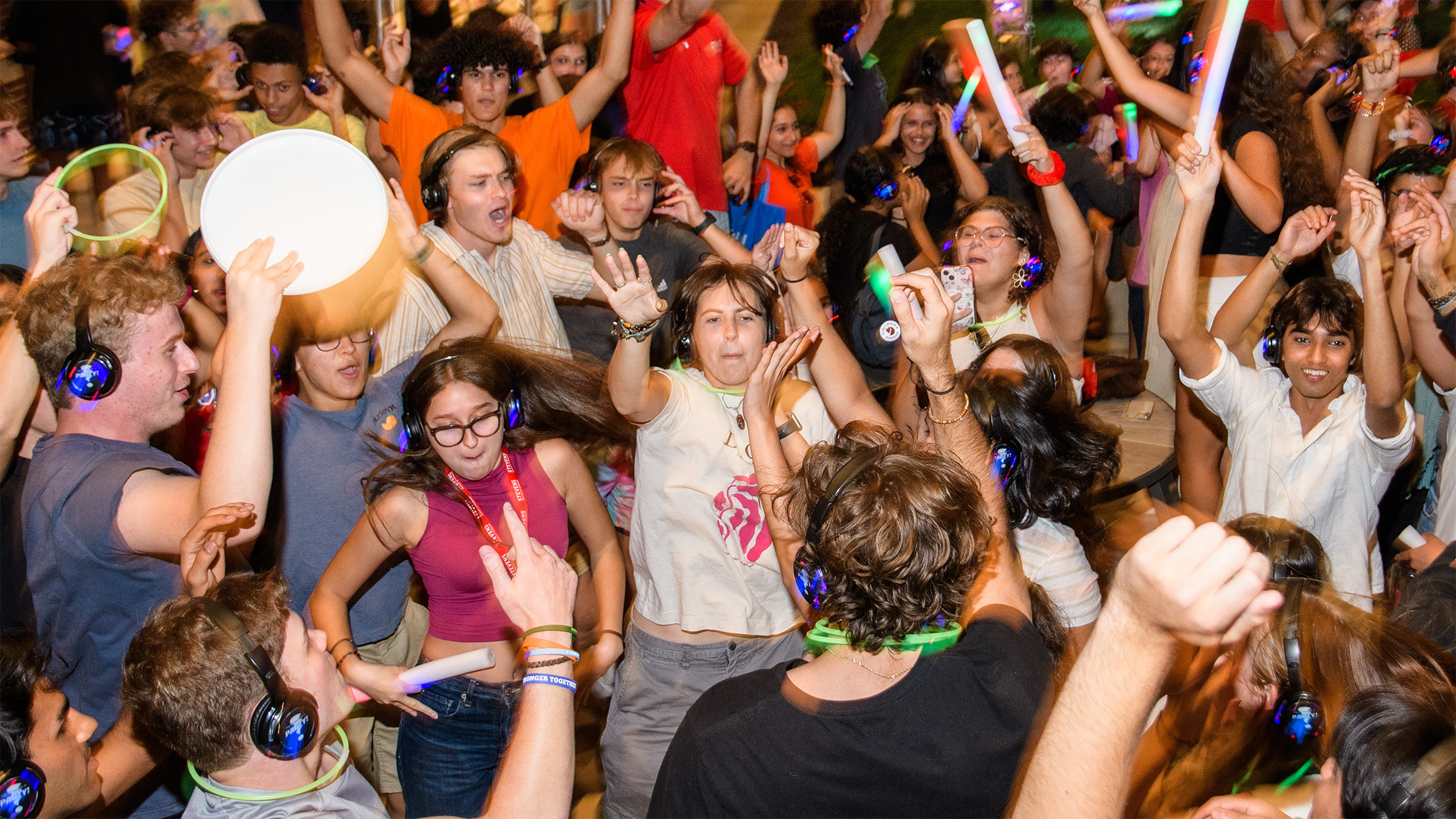 Crowd of students dance with headphones on and throw their hands in the air like they just don't care.