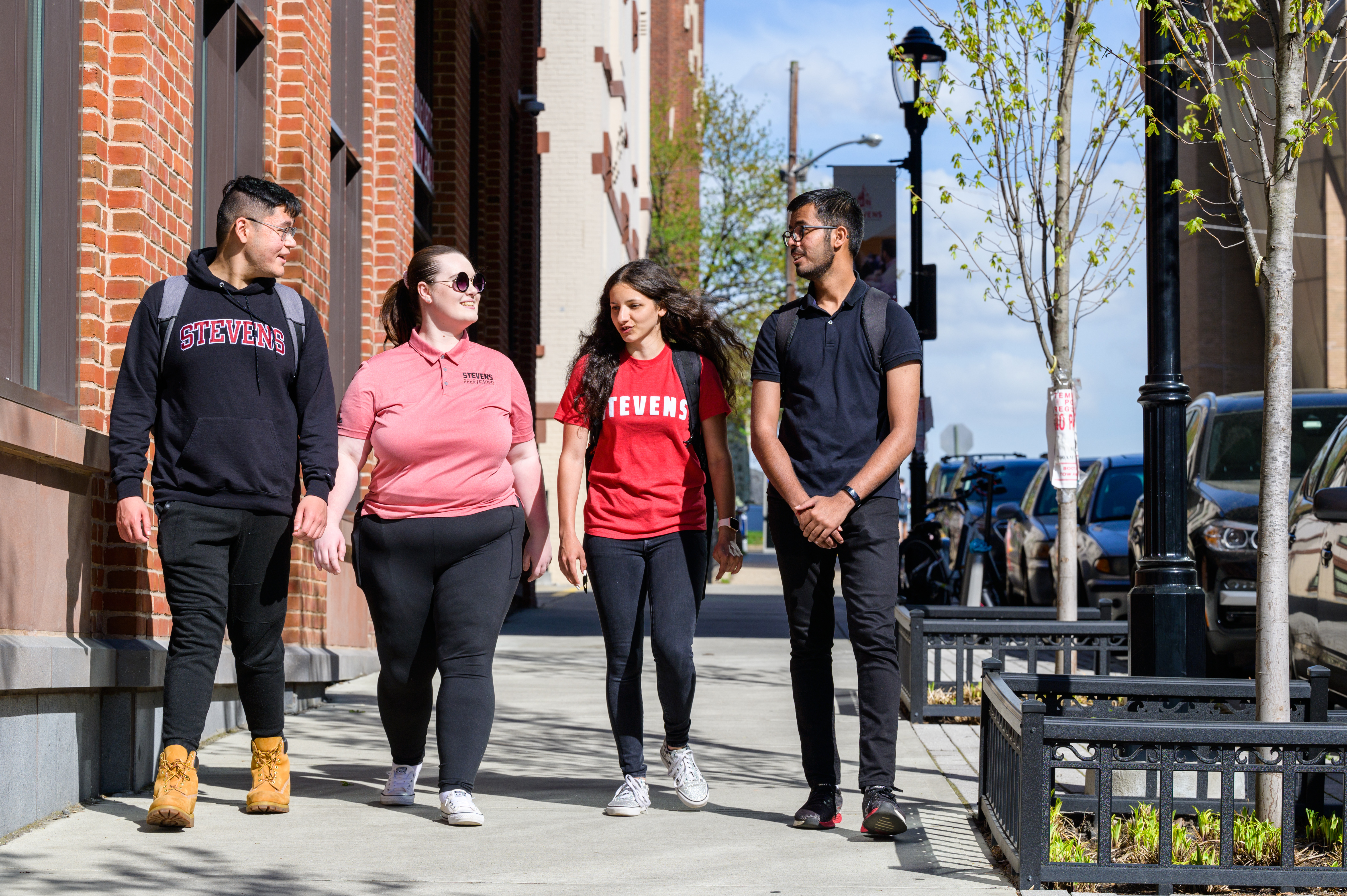 Four students walk on campus sidewalk in Stevens gear
