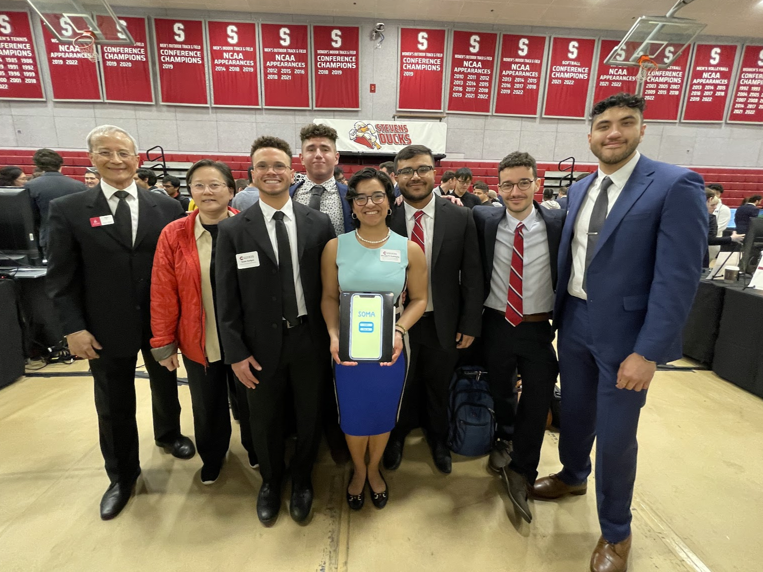 Advisor Kevin Lu, mentor Ommer Khaw and Soma team members Austin Hodges ’23, Jonathan Melamed ’23, Liz Samayoa ’23, Tahrim Imon ’23, Christian Diesen ’23 and Akash Rana ’23 stand together smiling, with Samayoa holding a tablet that reads "Soma"