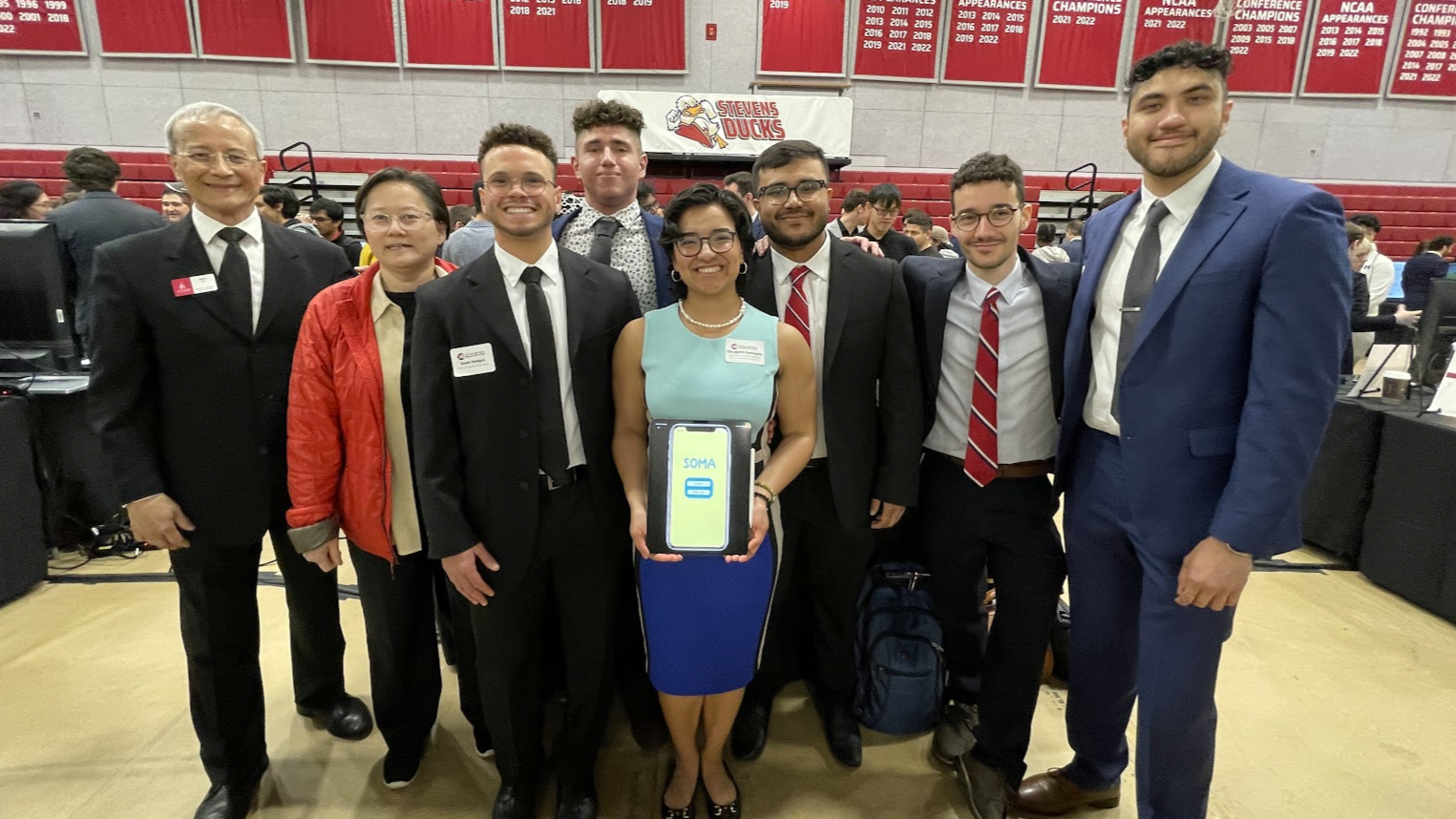 Advisor Kevin Lu, mentor Ommer Khaw and Soma team members Austin Hodges ’23, Jonathan Melamed ’23, Liz Samayoa ’23, Tahrim Imon ’23, Christian Diesen ’23 and Akash Rana ’23 stand together smiling, with Samayoa holding a tablet that reads "Soma"