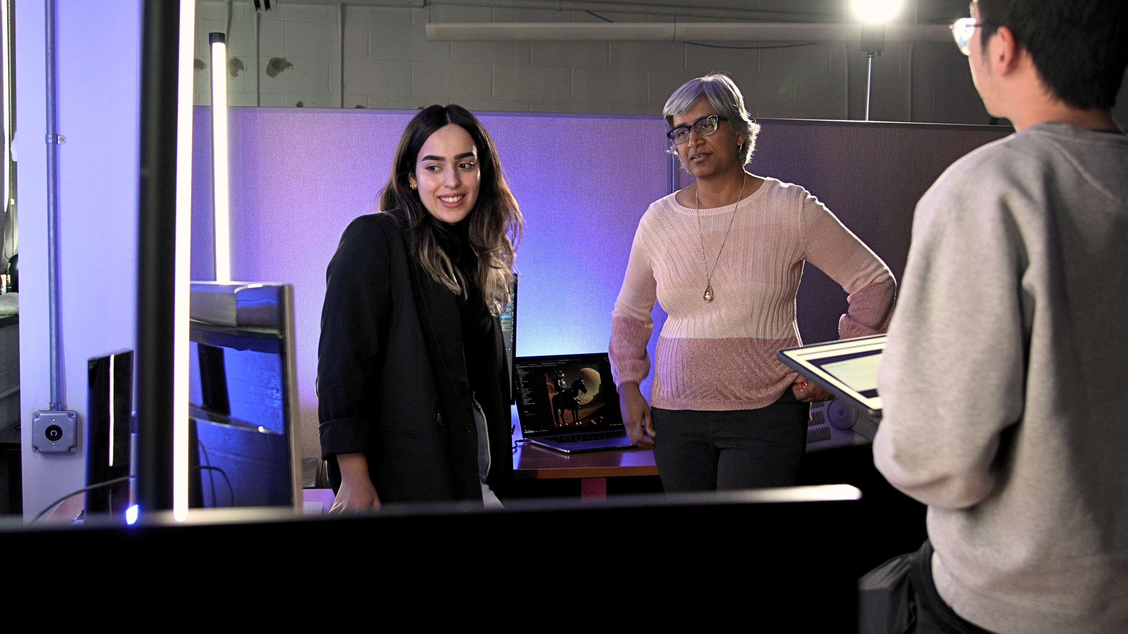Professor Koduvayur Subbalakshmi, at right, works with students inside of a darkened lab.