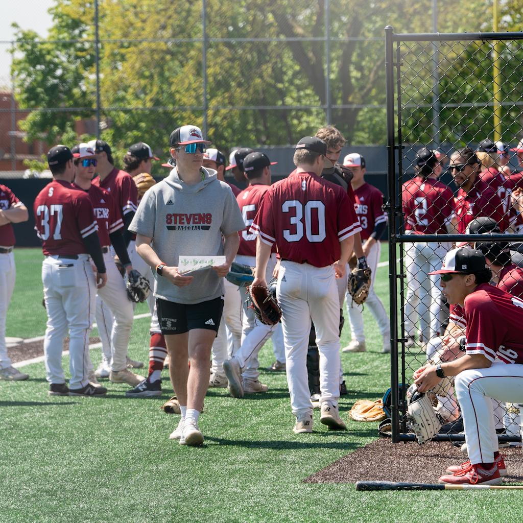 Vaughn Weber stands in the foreground of a group of Stevens baseball players on the field prior to a game.
