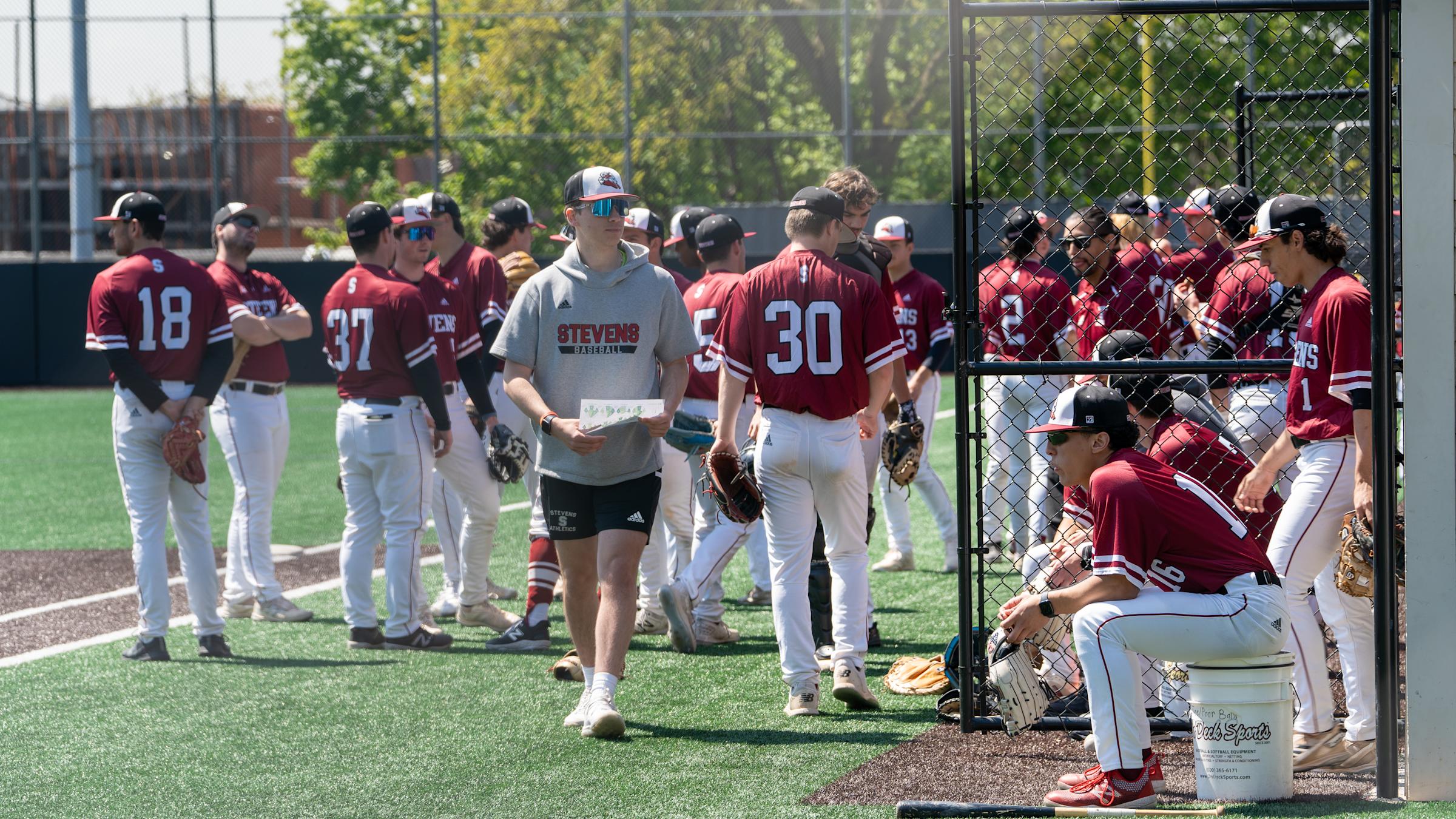 Vaughn Weber stands in the foreground of a group of Stevens baseball players on the field prior to a game.