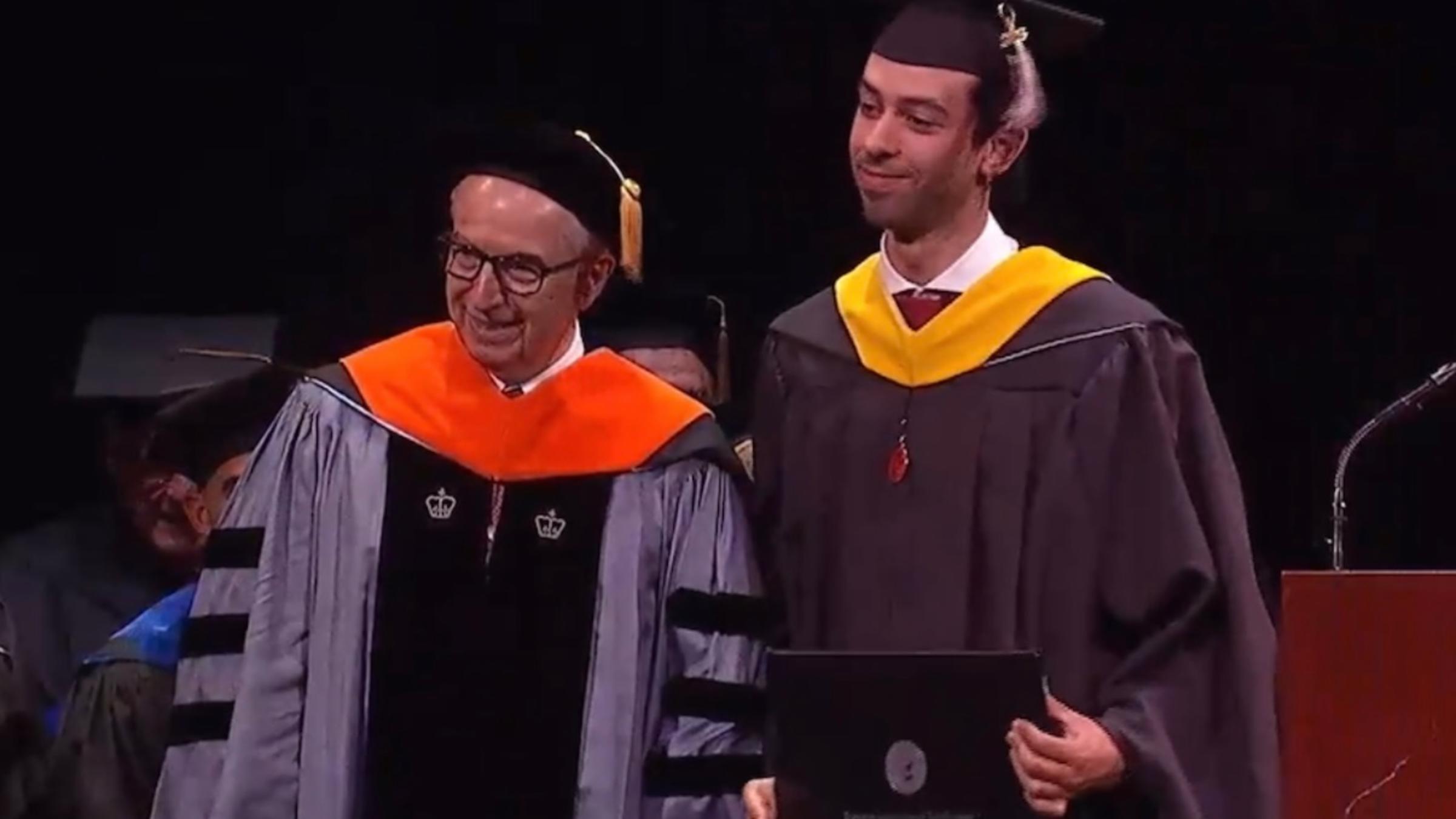 Dean Gregory Prastacos and Ahmed Ouerghemi pose for a photo at graduation. Ahmed is holding his diploma.