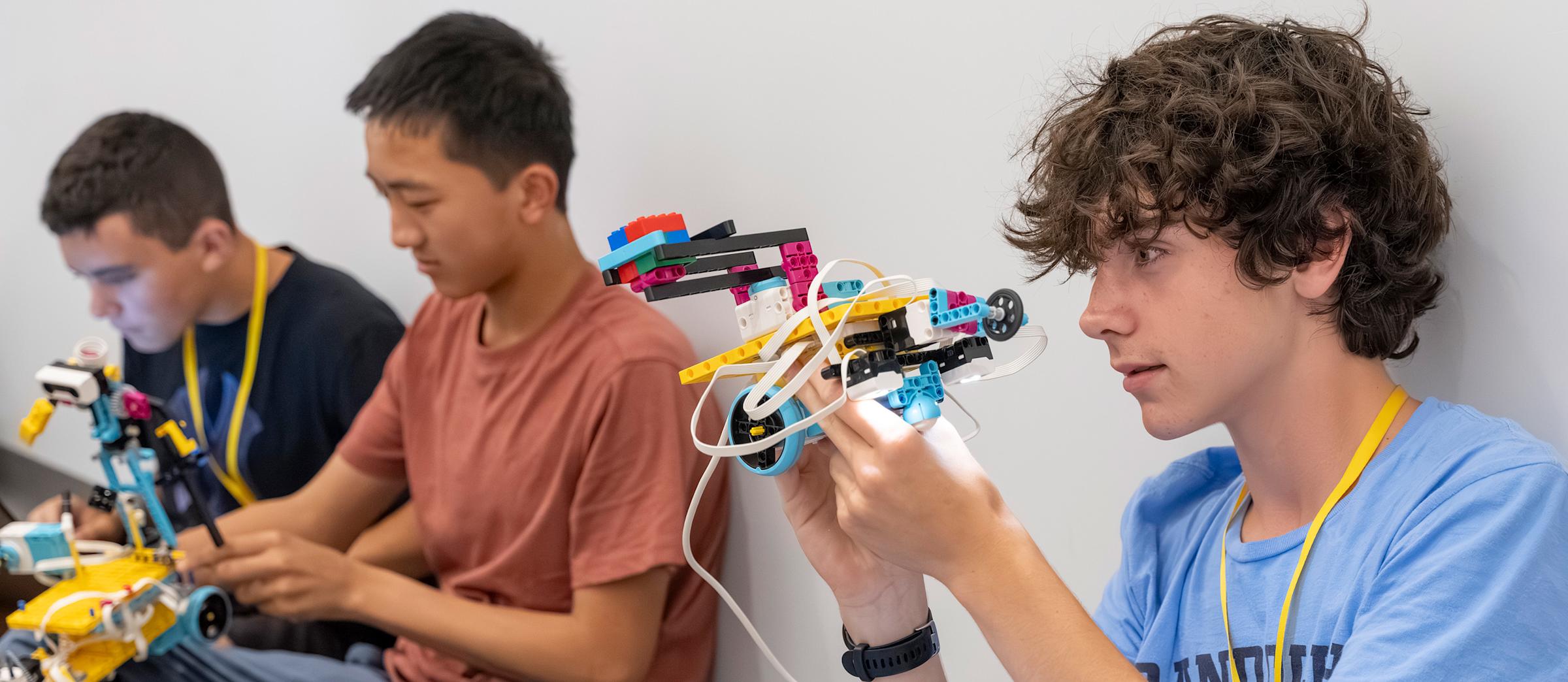 Three pre-college students concentrate on building their own robot models