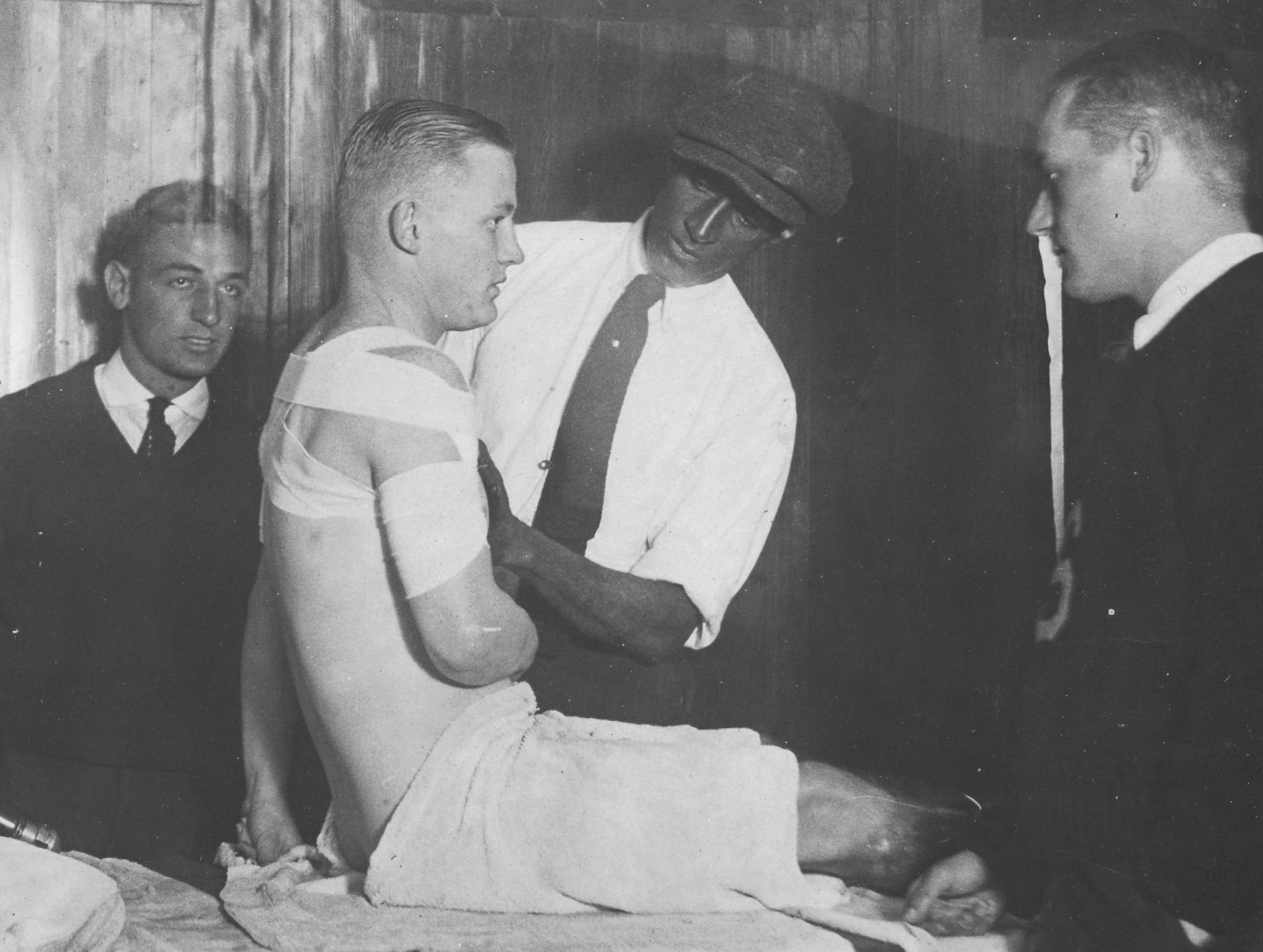 Old photo of a Stevens football player being bandaged around the arm.