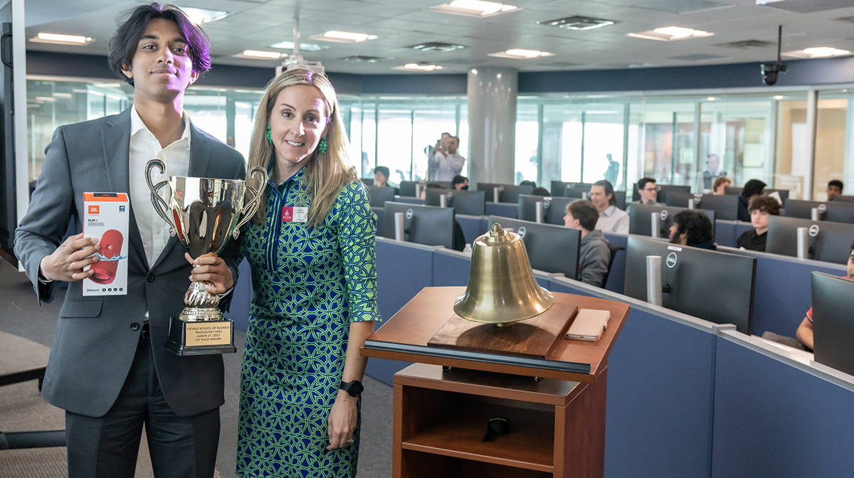 Trading Day winner Vinay Venkatesh stands next to Lindsay Hartelius , holding a trophy and speaker prize