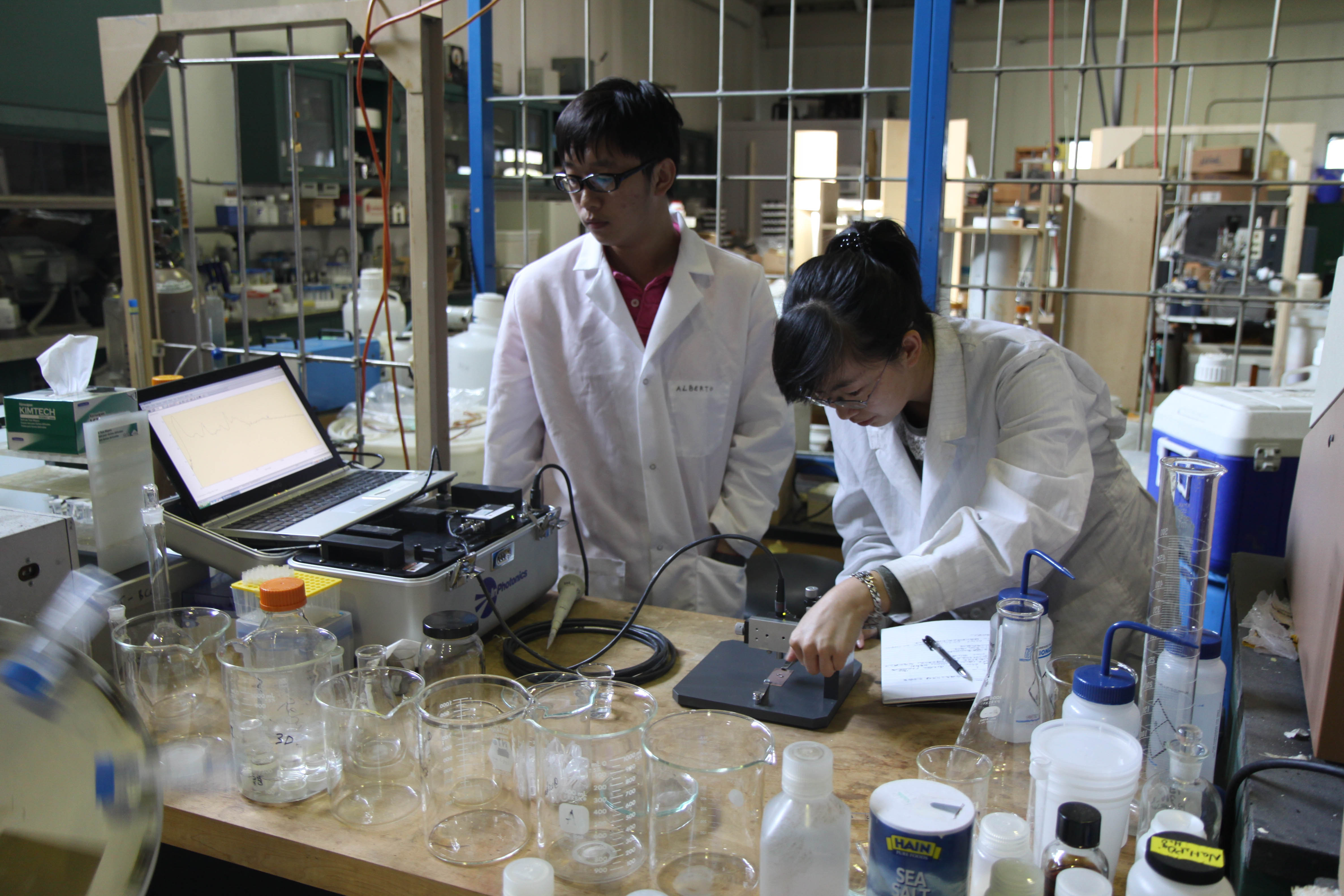 A student working with chemical equipment by a window showing the Empire State Building.