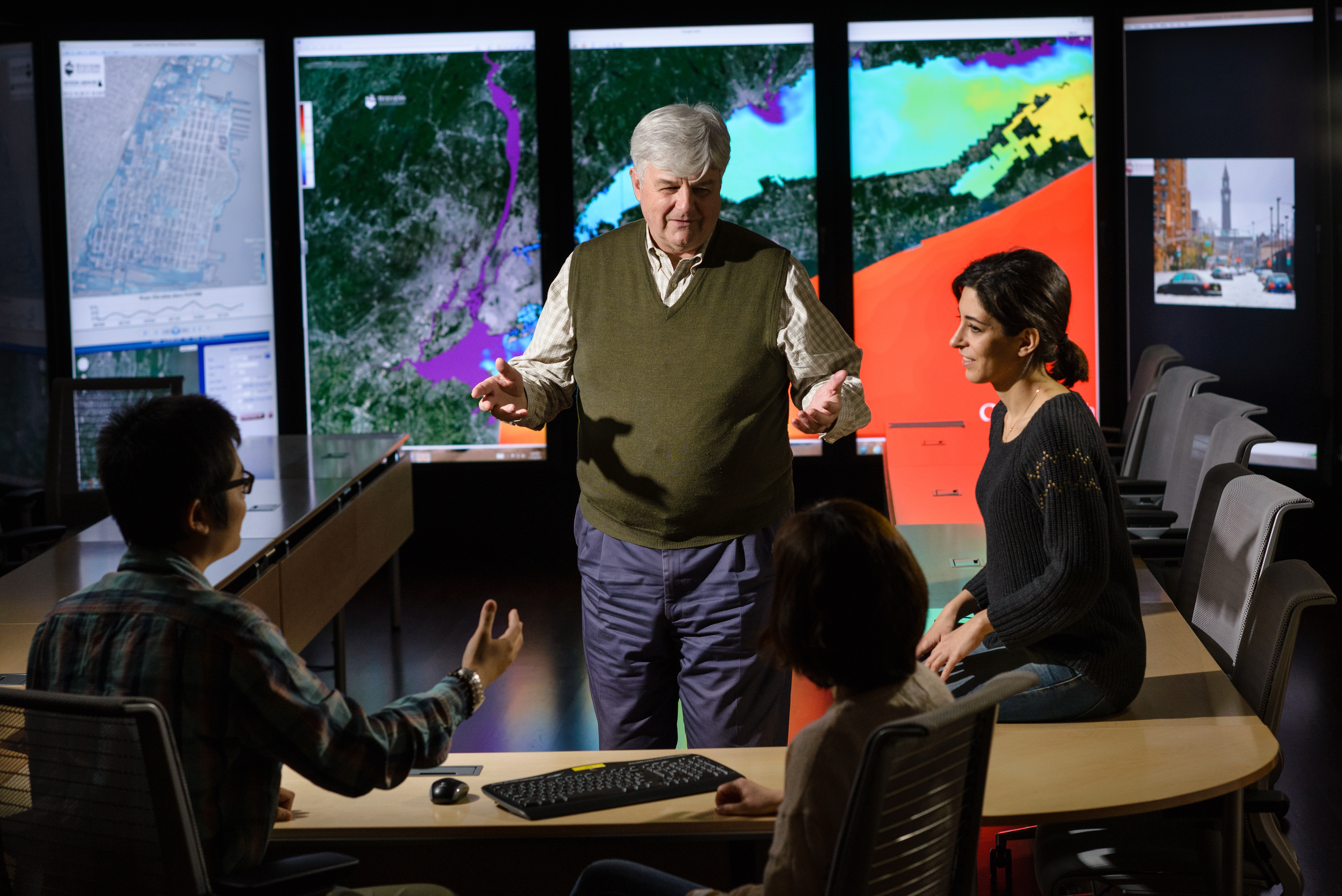 A professor in the immersion lab with satellite images of Hoboken and New York Harbor in the background