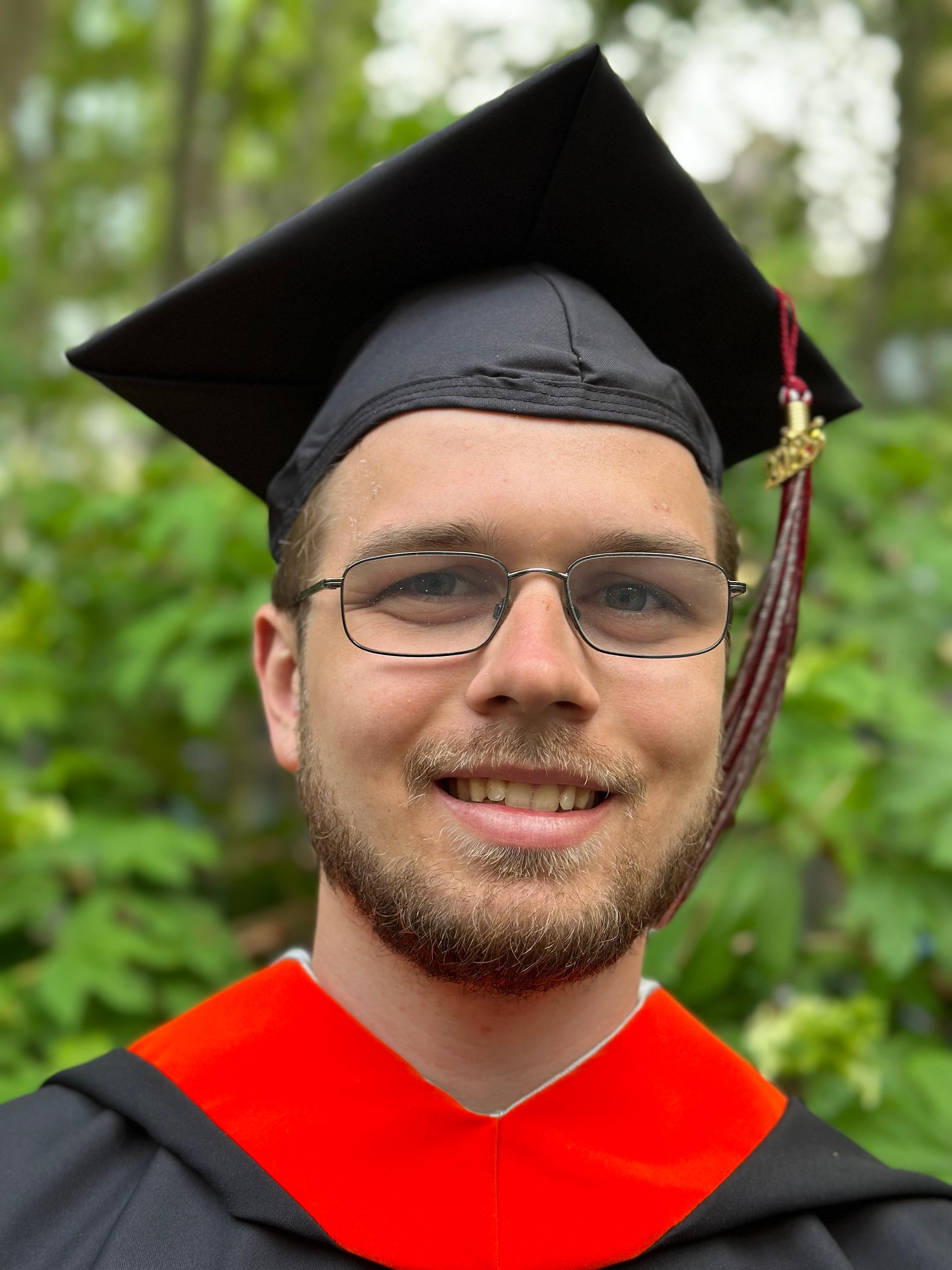 Erik Cederstav ’23 smiles outside while wearing mortarboard and graduation robe