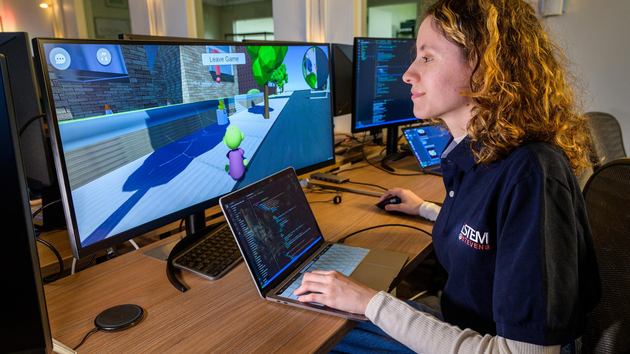 Student works on a video game on a wide screen monitor in a computer lab.