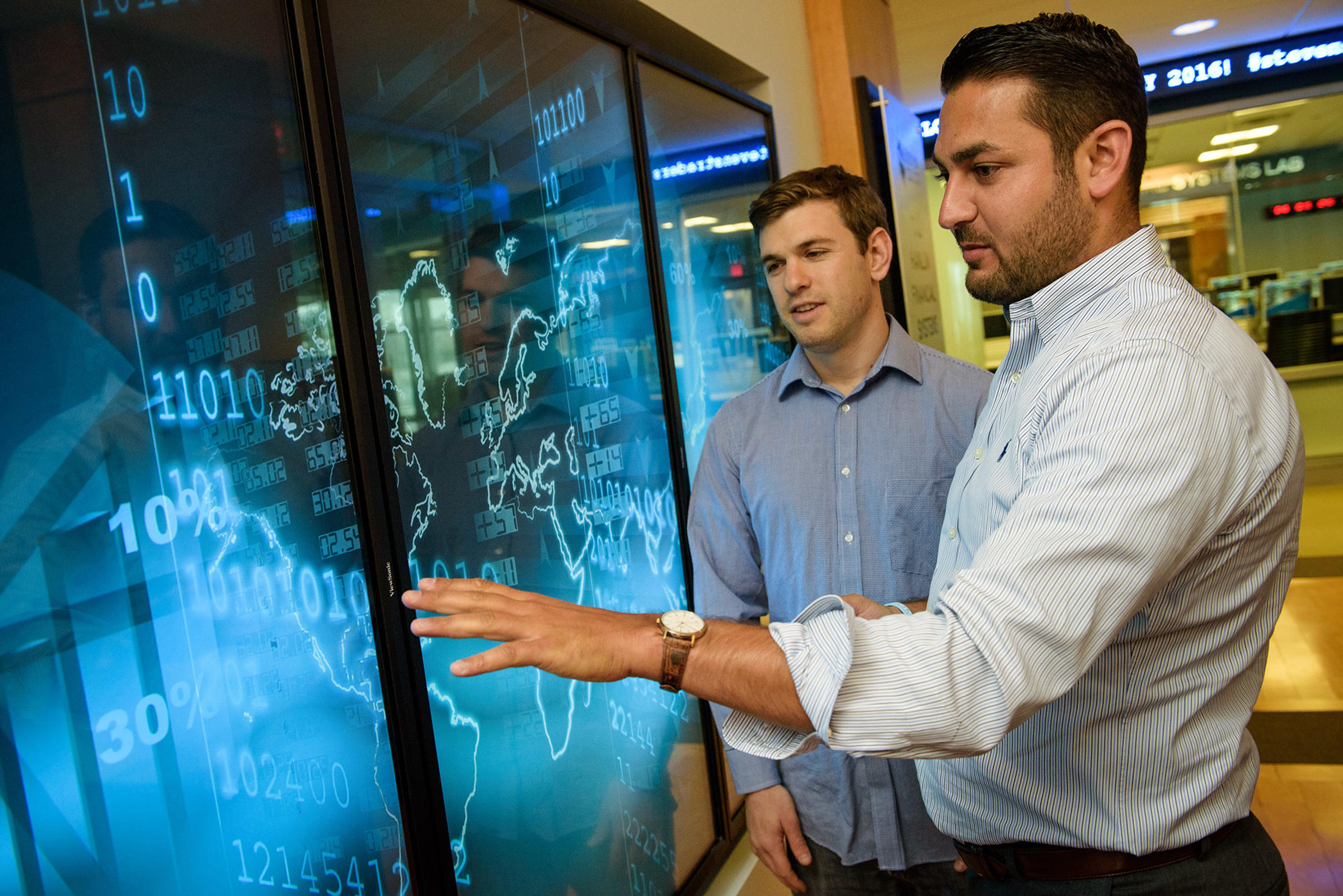 two men in front of digital screen