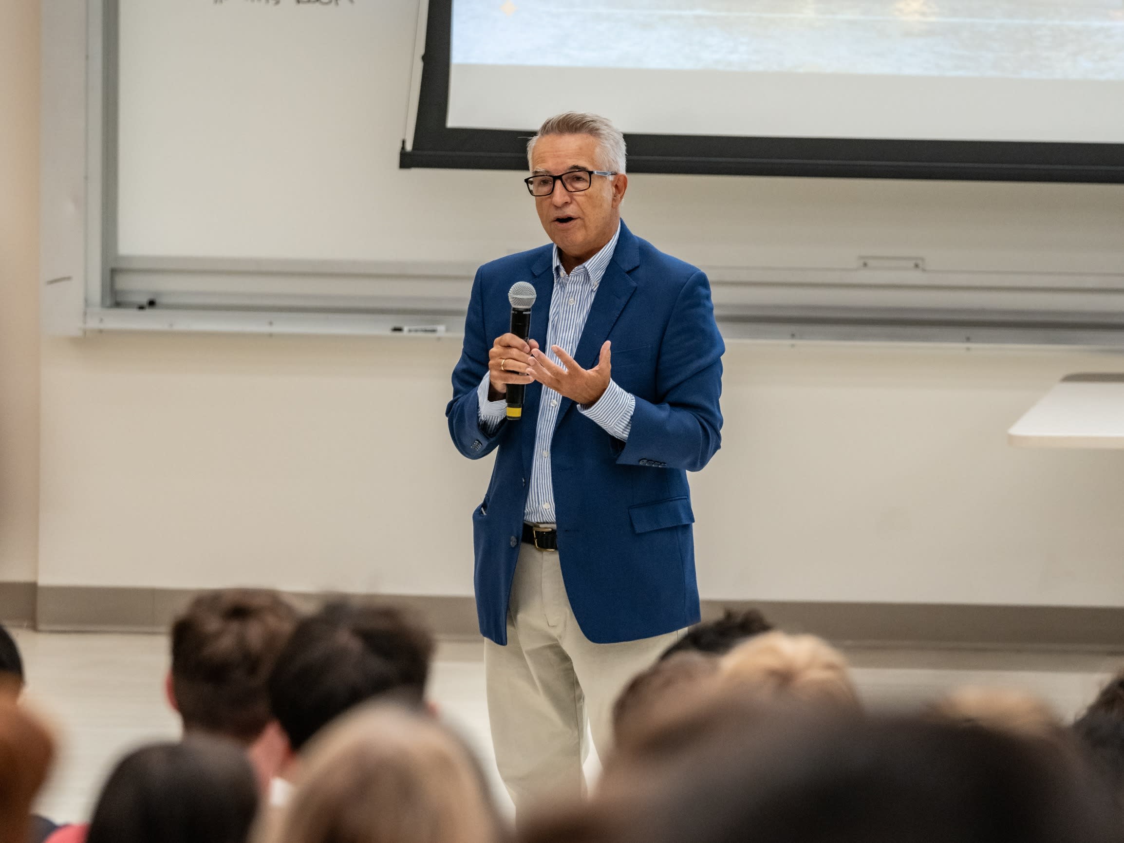 Close-up of SSB Dean Gregory Prastacos speaks to first-year students holding a microphone.