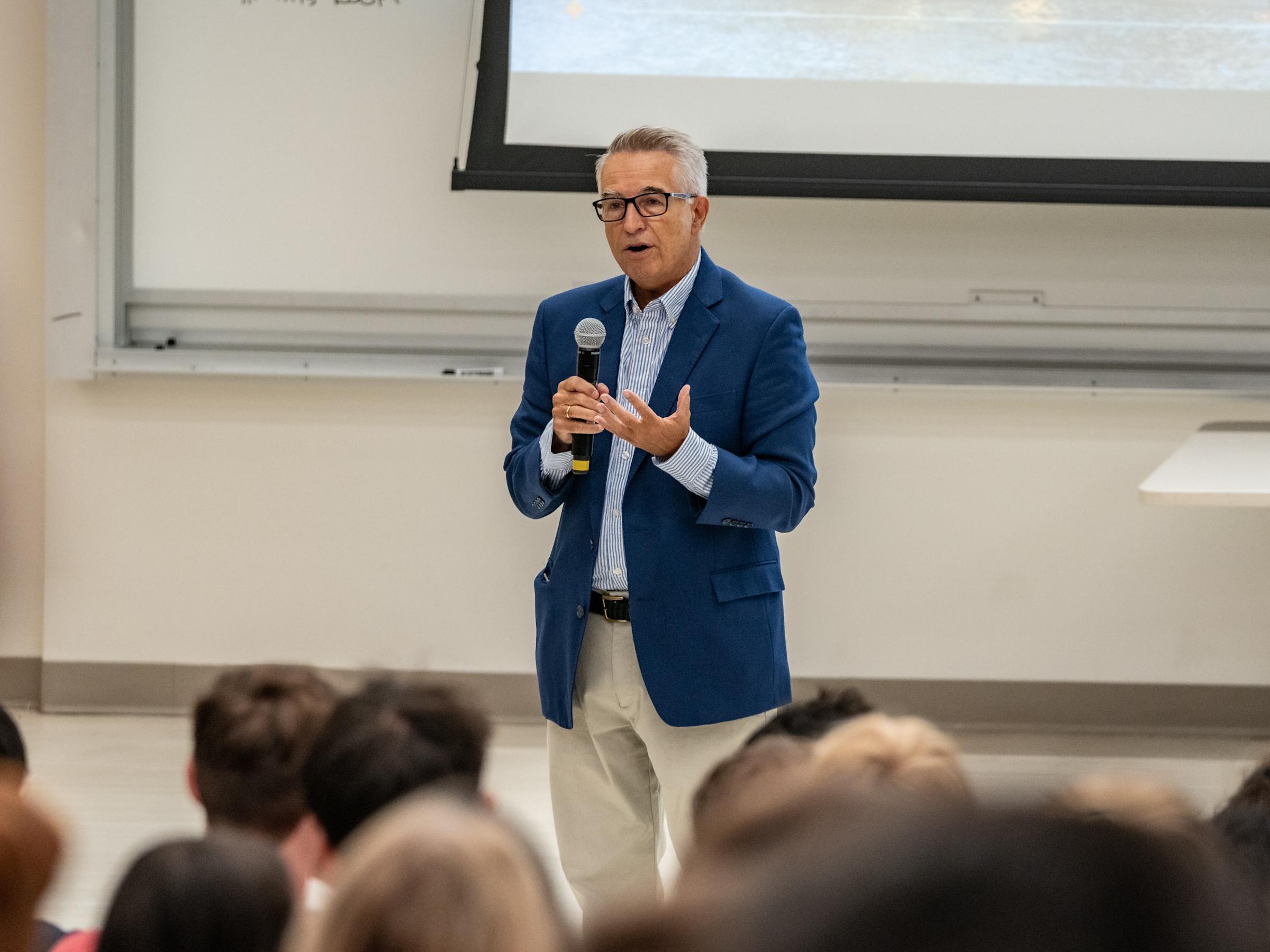 Close-up of SSB Dean Gregory Prastacos speaks to first-year students holding a microphone.