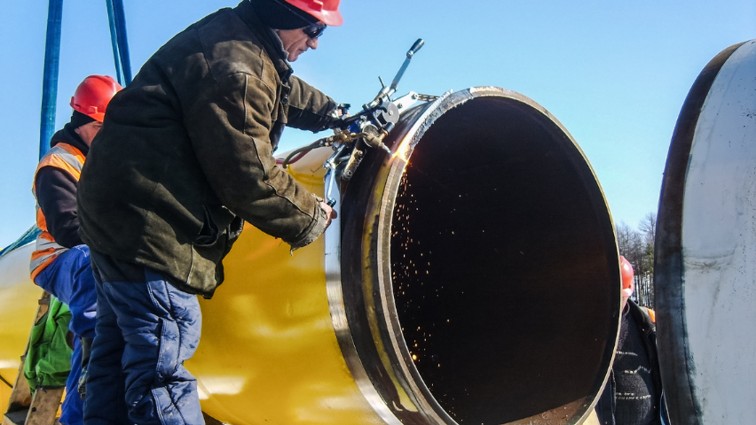 A stock image of pipeline workers connecting two pieces of pipeline.