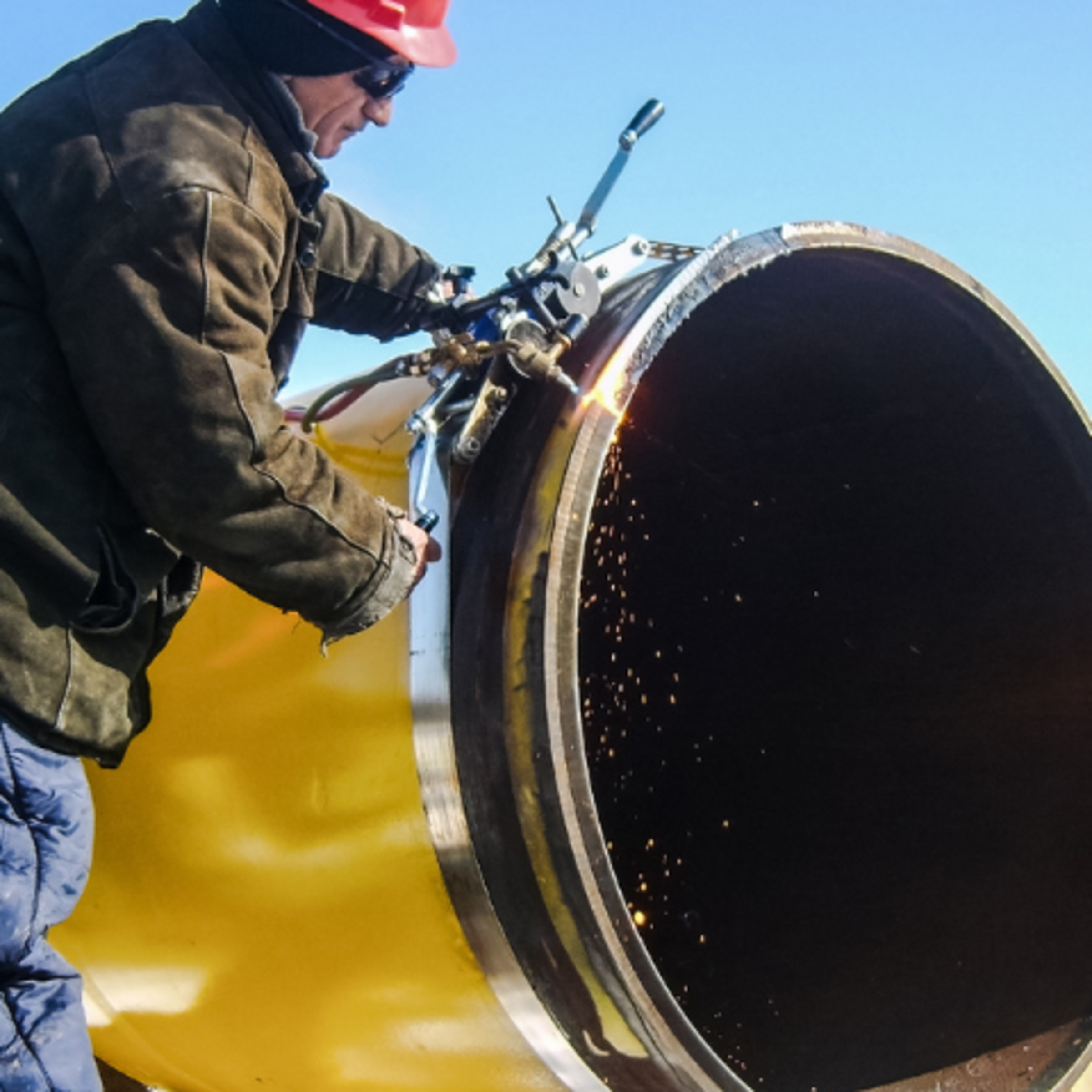 A stock image of pipeline workers connecting two pieces of pipeline.