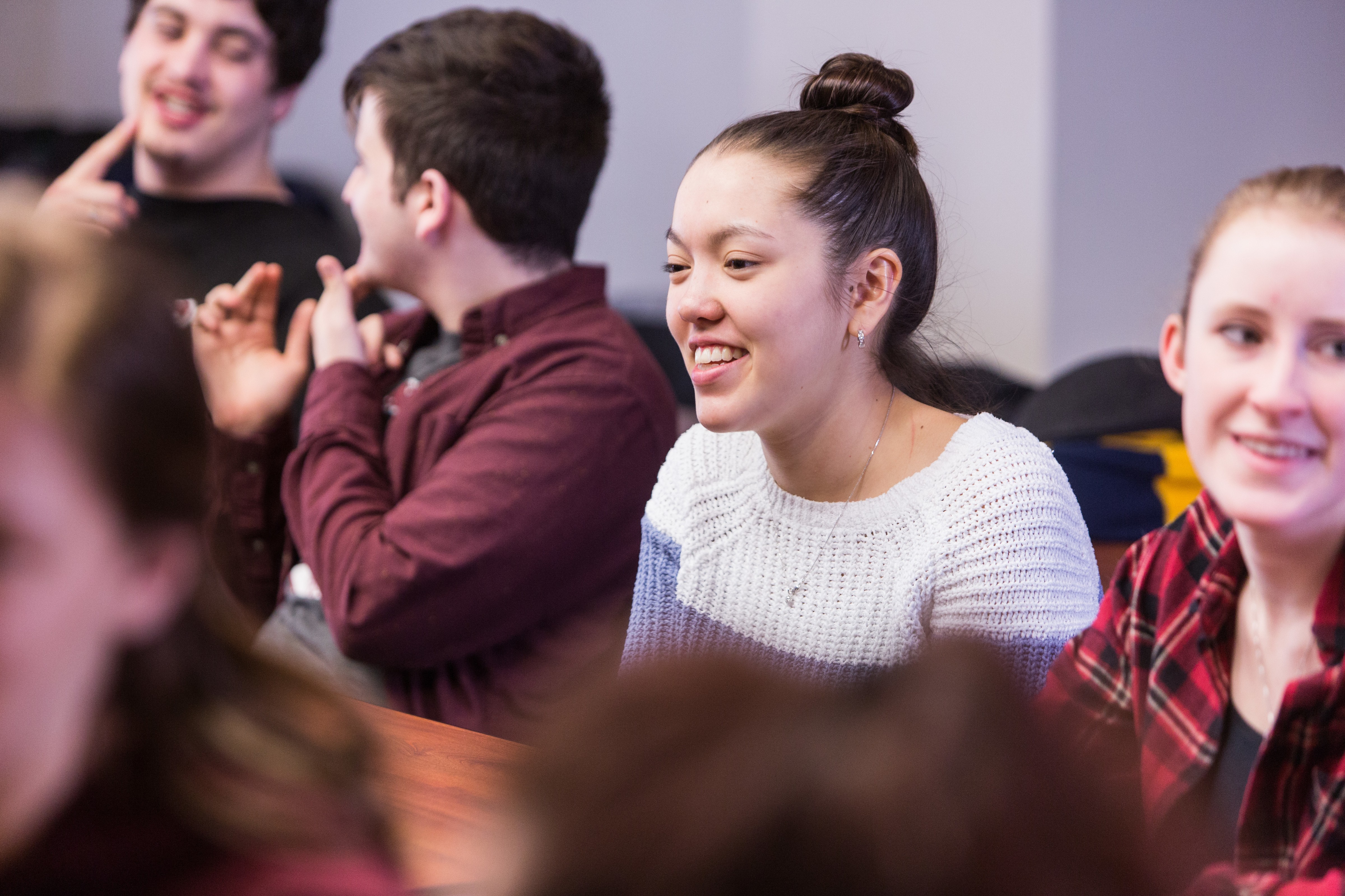 Female student smiling in a classroom surrounded by male and female colleagues