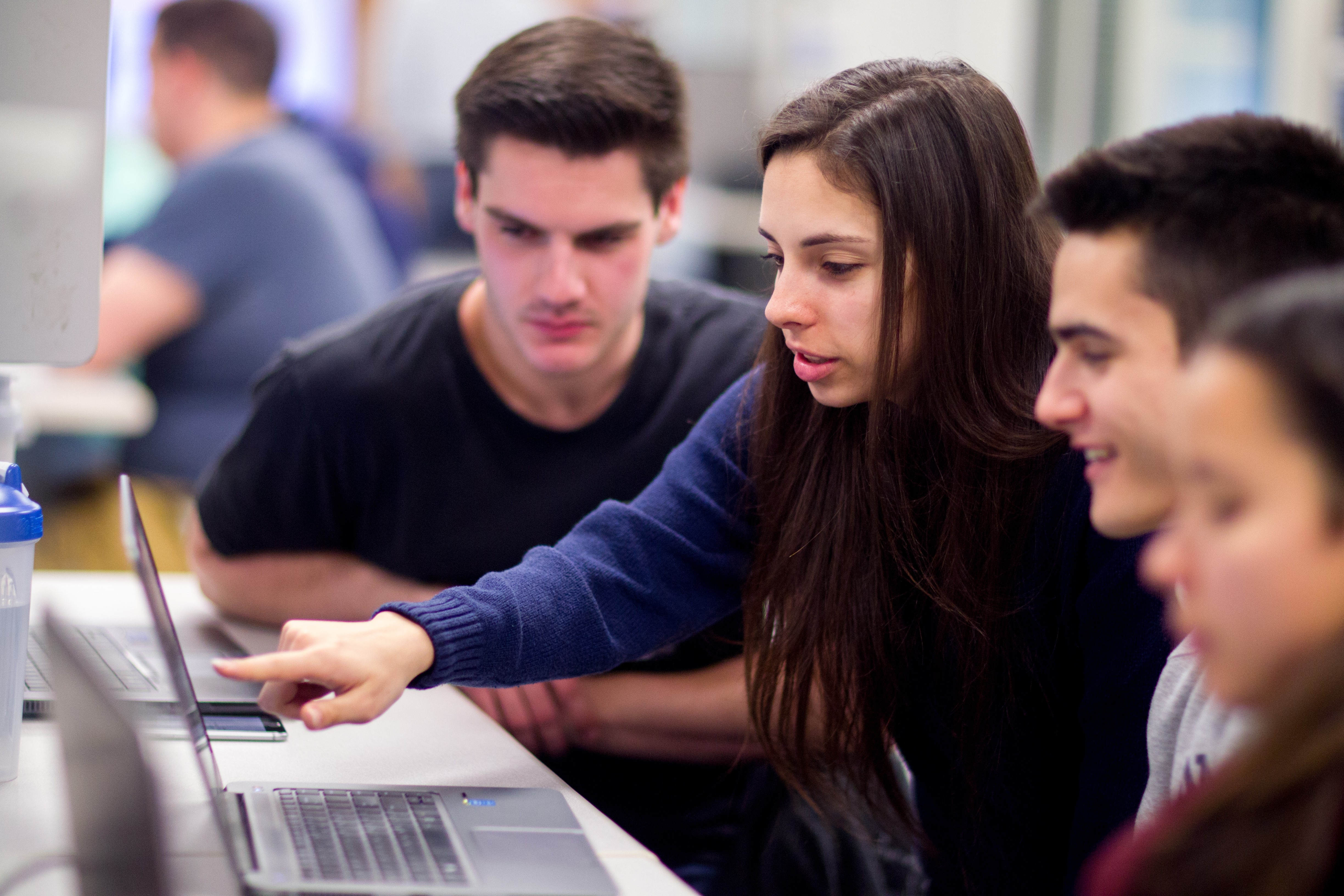 Students in classroom pointing at laptop