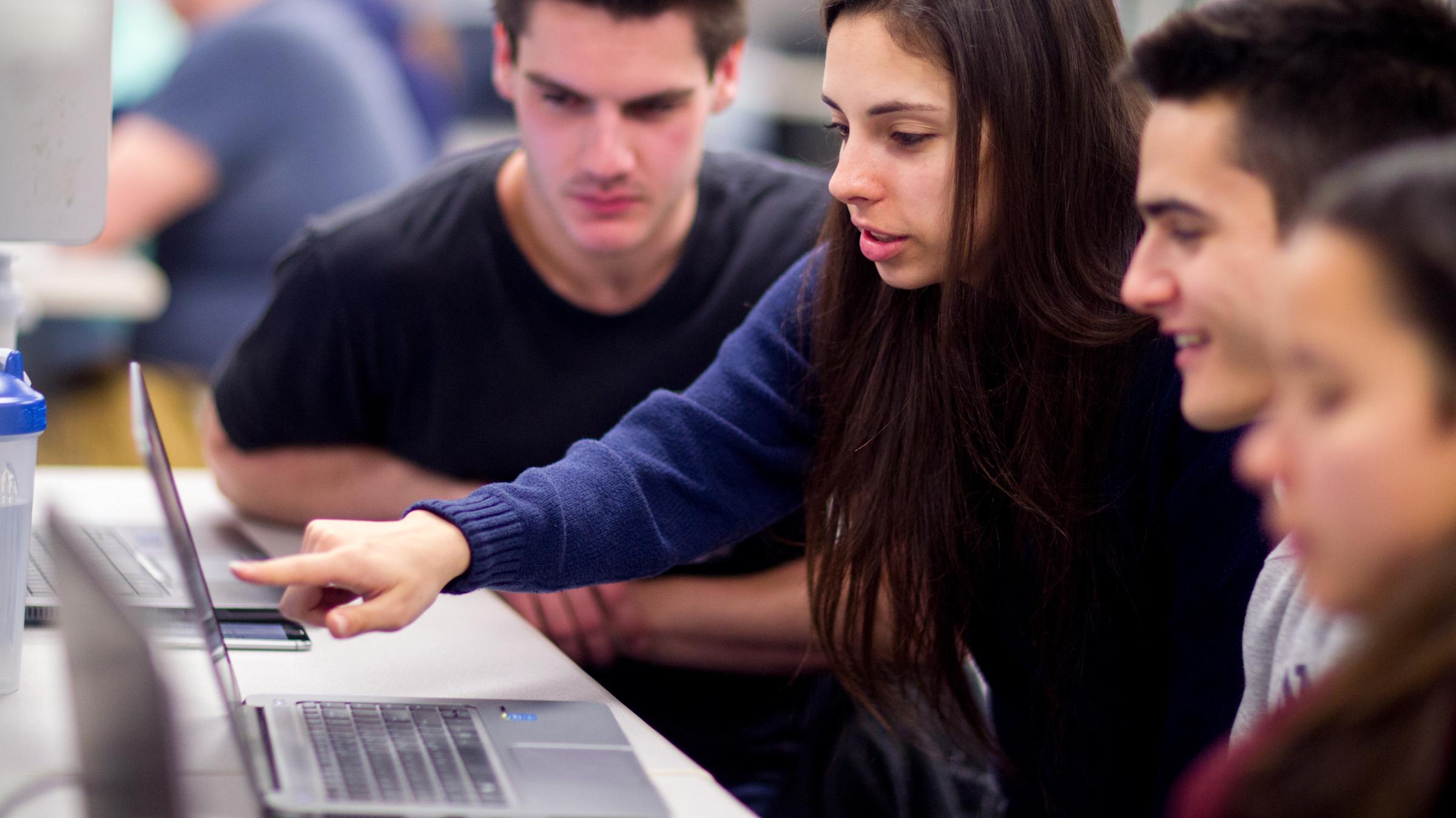 Students in classroom pointing at laptop