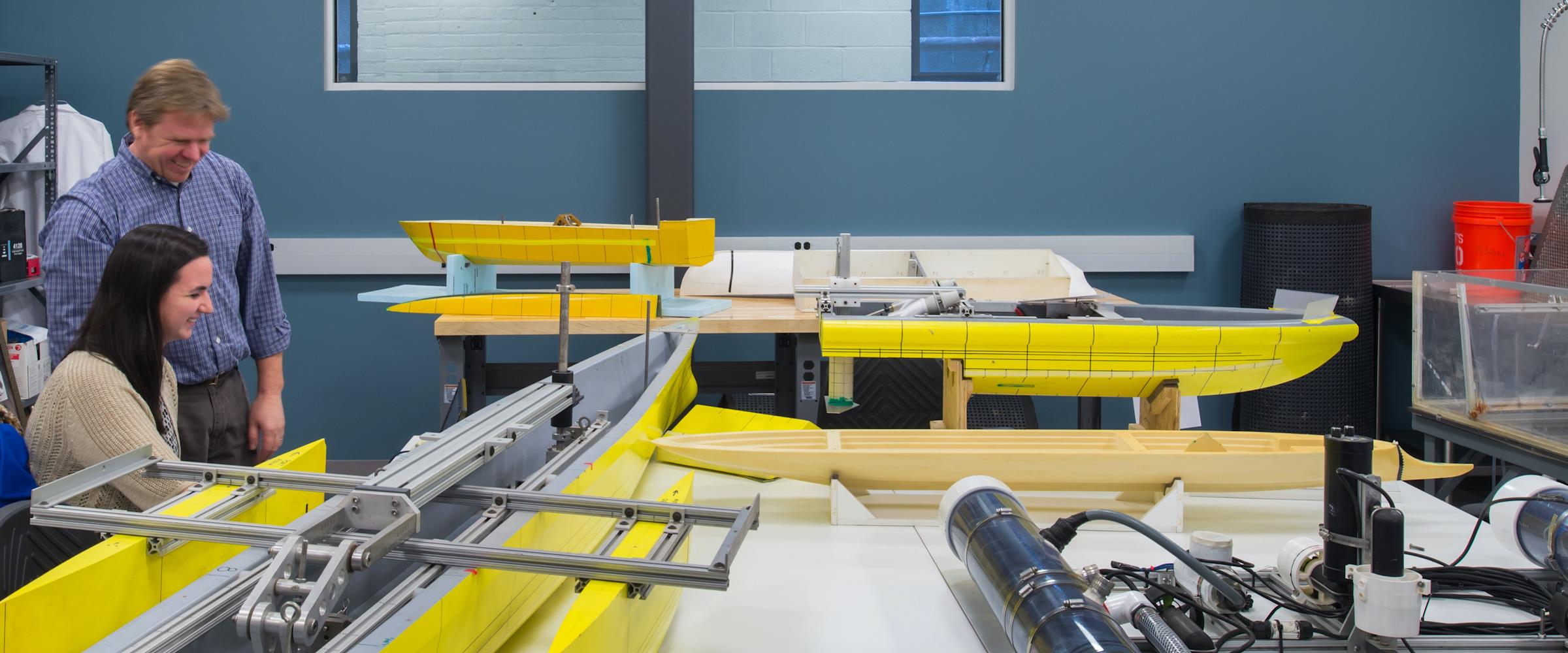 student and professor in lab with boats