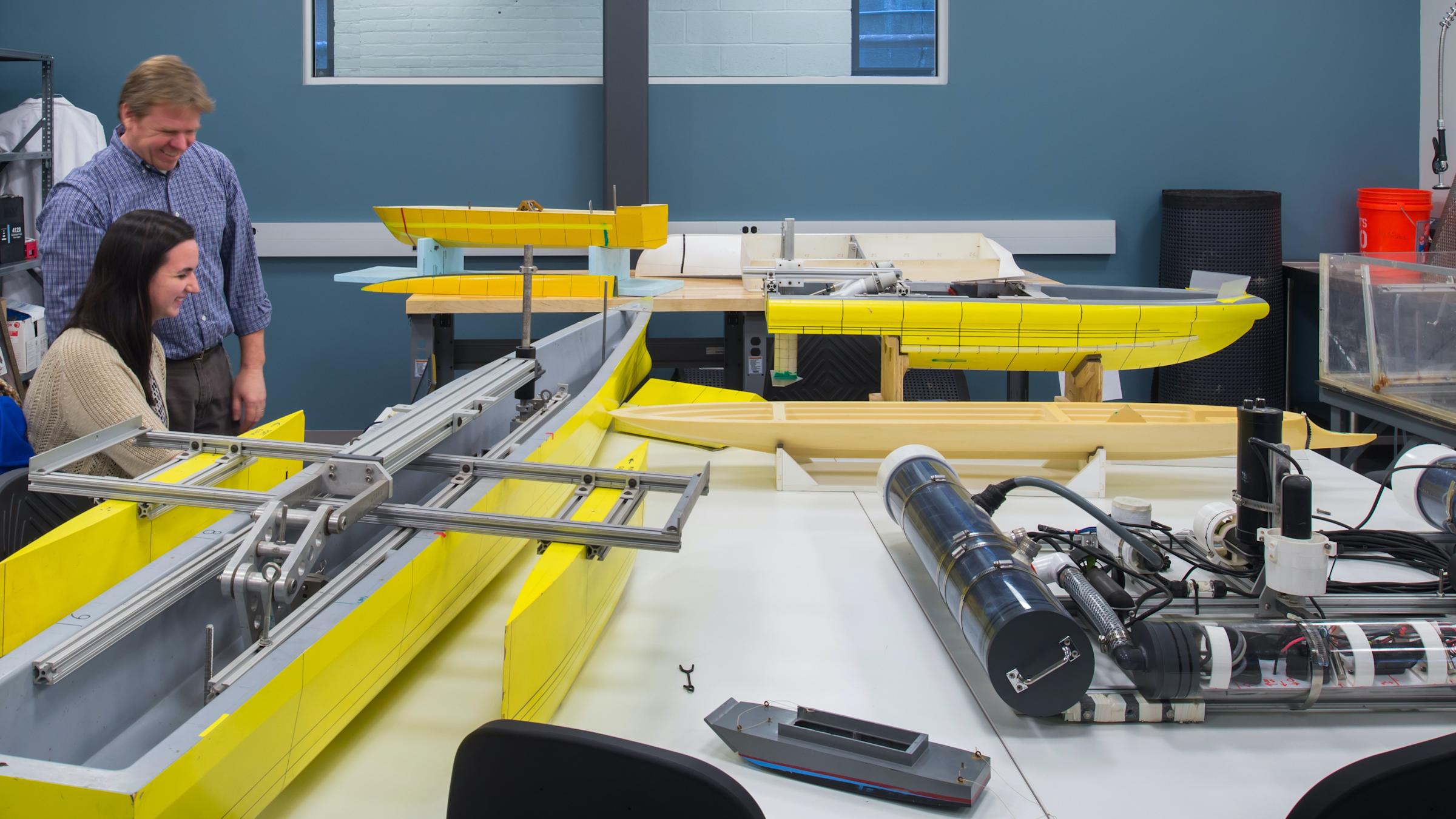 student and professor in lab with boats