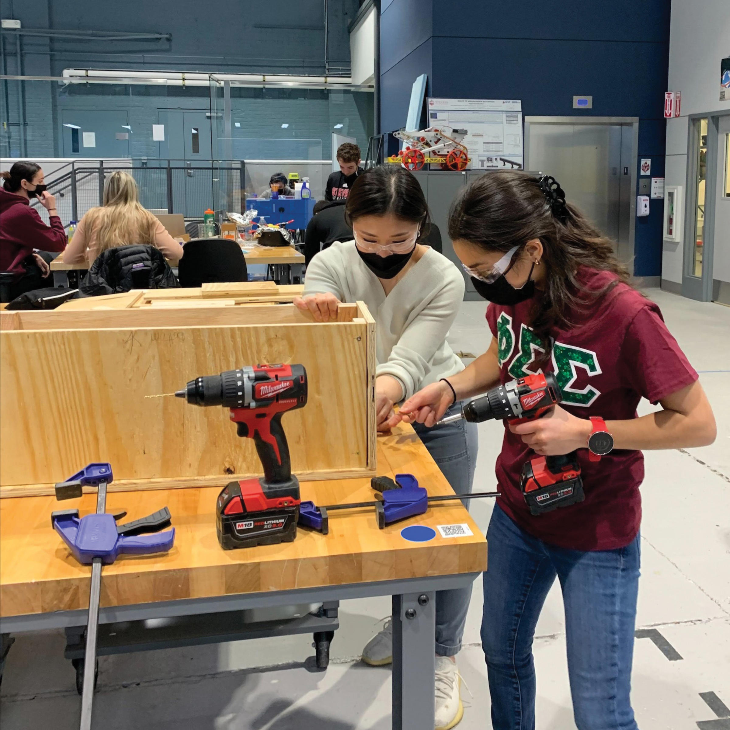 Two students in masks construct a box in the ABS facility.